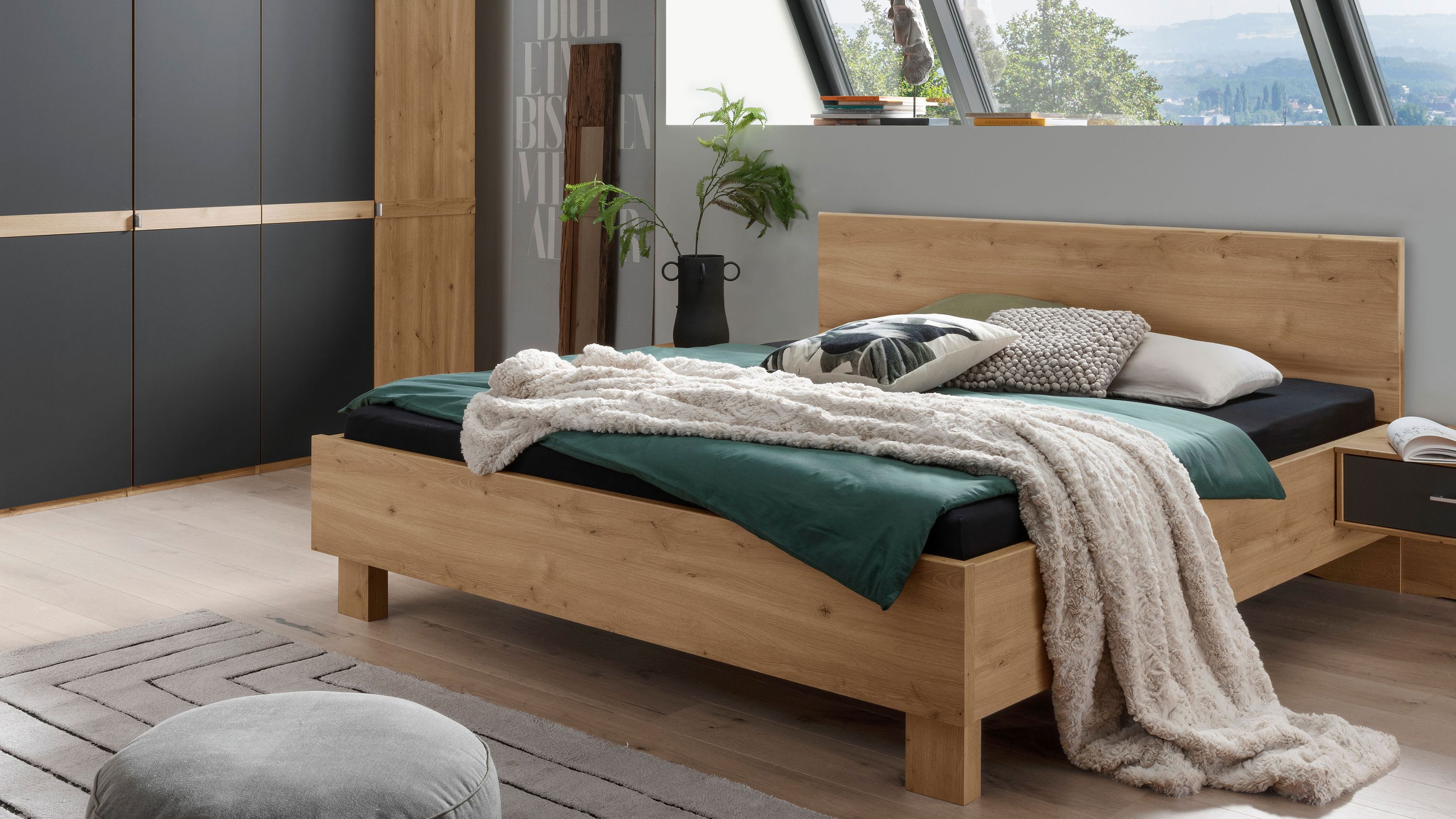 Bettgestell mit rechteckigem Kopfteil in heller Holzoptik mit Bettdecke und Kissen in einem modernen Schlafzimmer