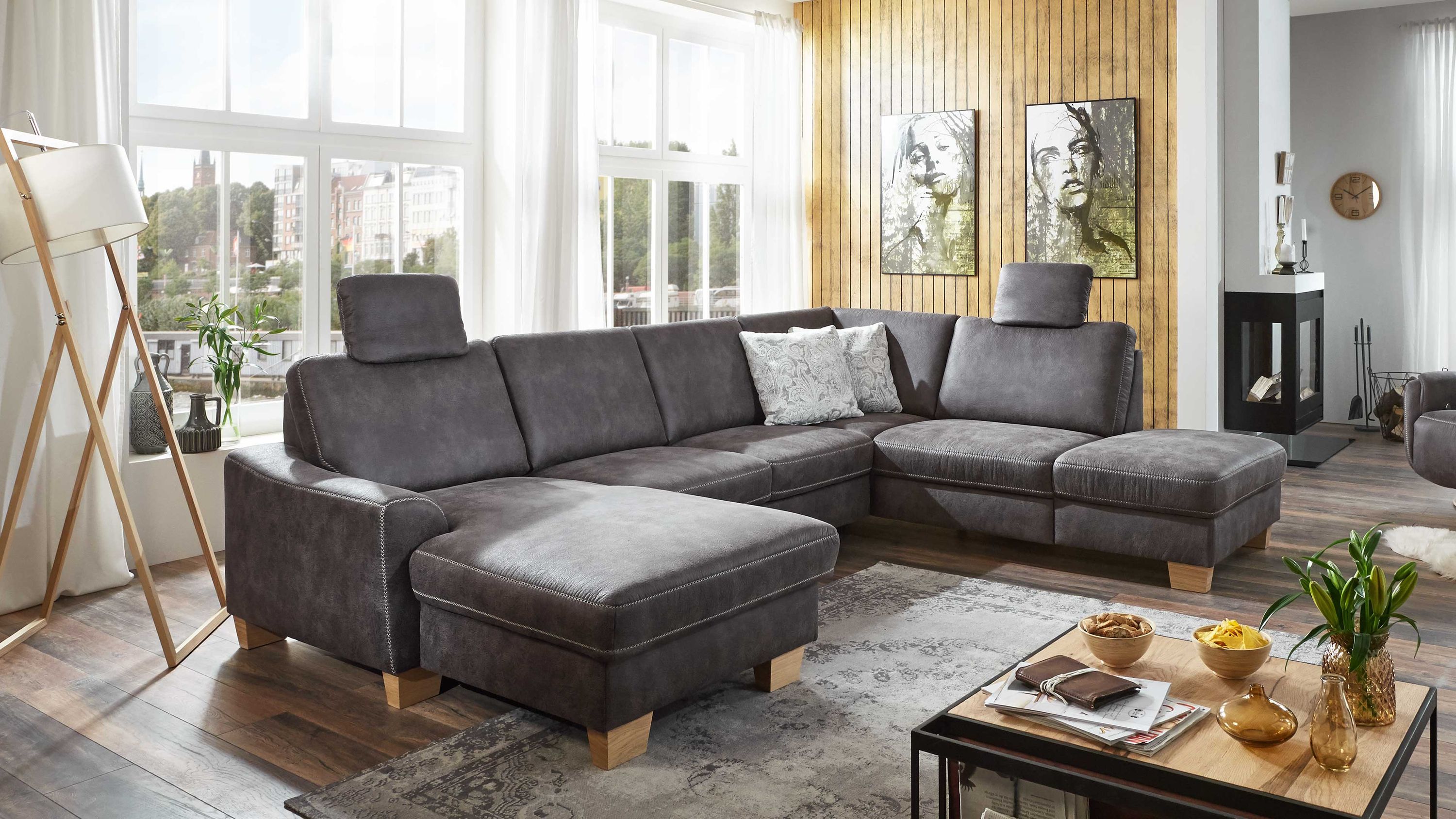 Ecksofa mit grauem Mikrofaserbezug und Holzfüßen in modernem Wohnzimmer mit Teppich und Dekokissen