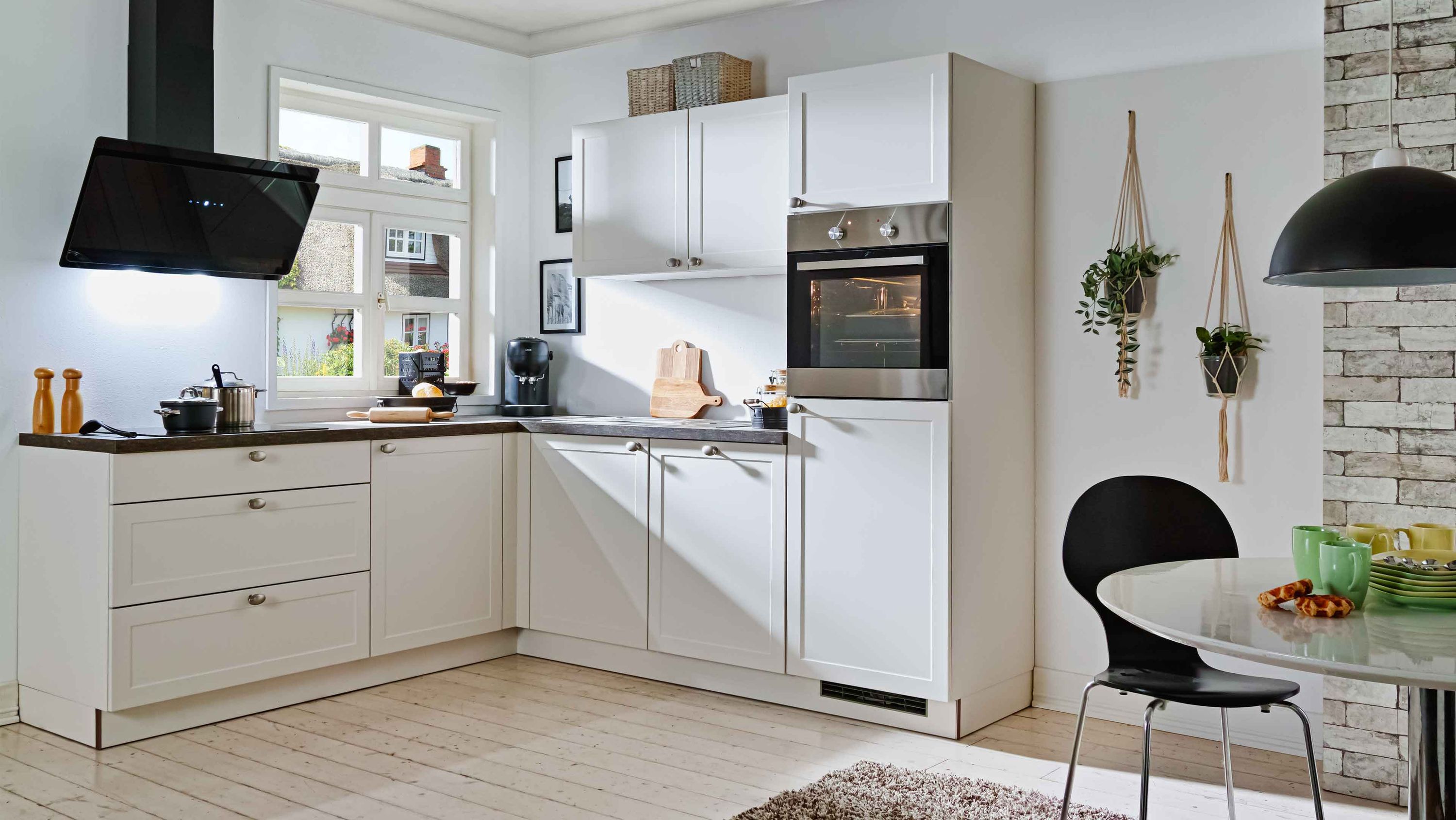 Moderne L-förmige Küche in Weiß mit schwarzen Akzenten und eingebautem Backofen.