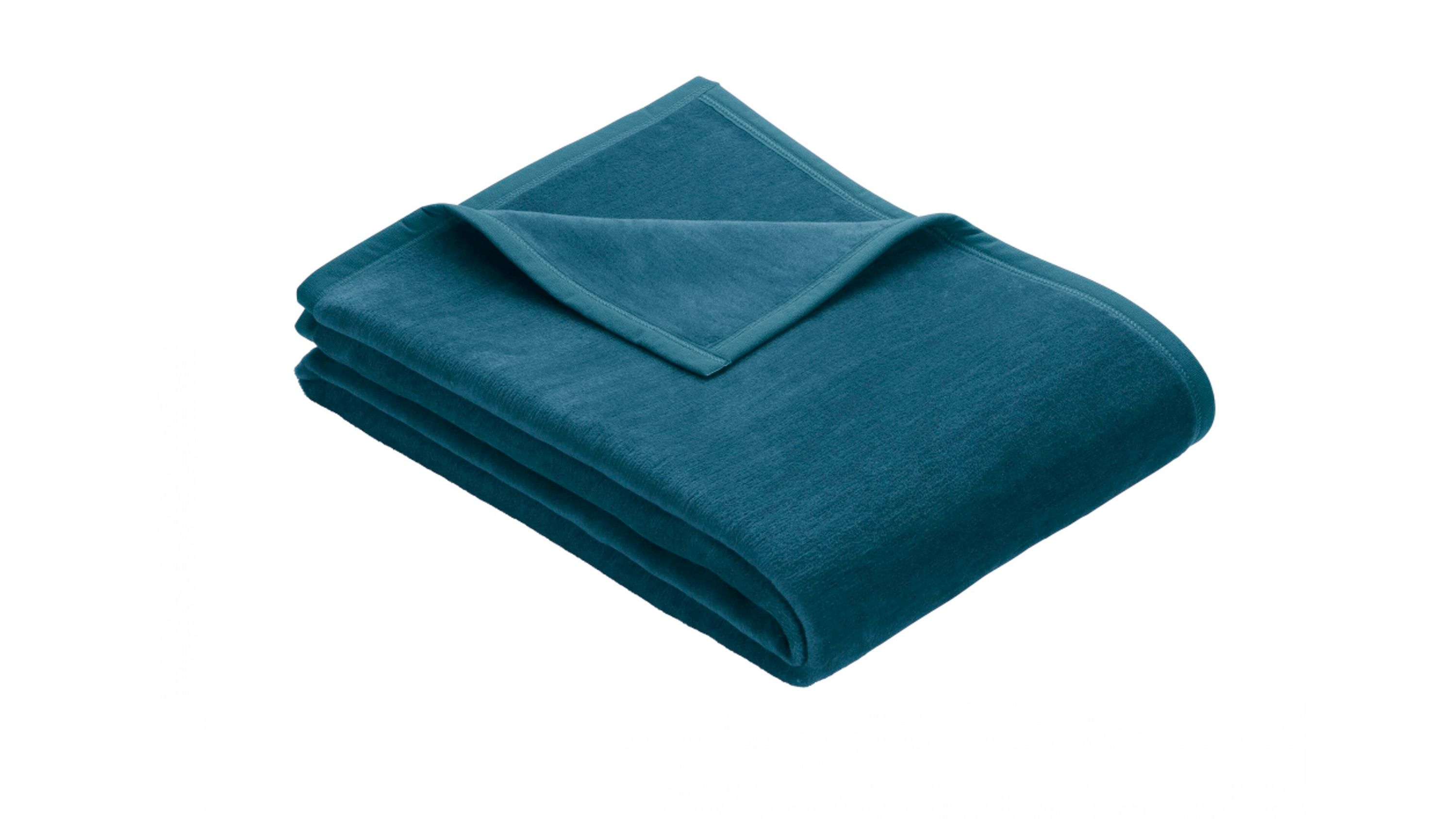Gefaltete Fleecedecke in petrolblauer Farbe mit eingefasstem Rand