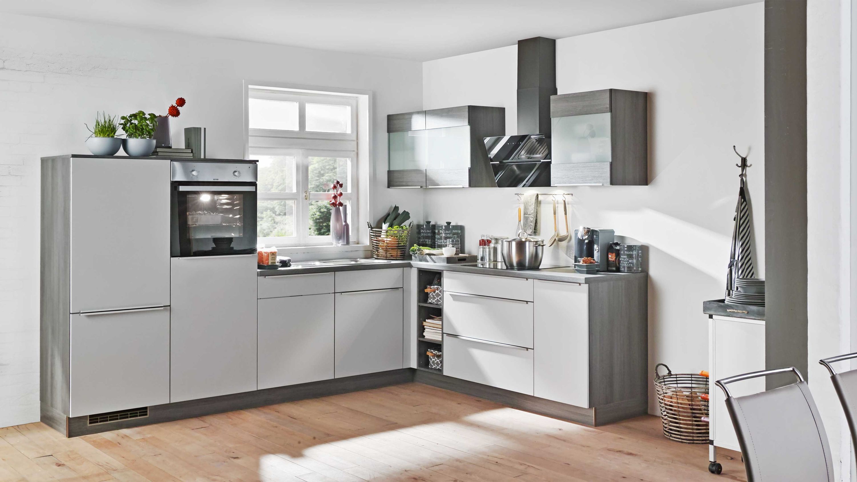 Moderne L-Küche in Grau mit Hochglanzfronten Einbaugeräten und Glas-Hängeschränken.