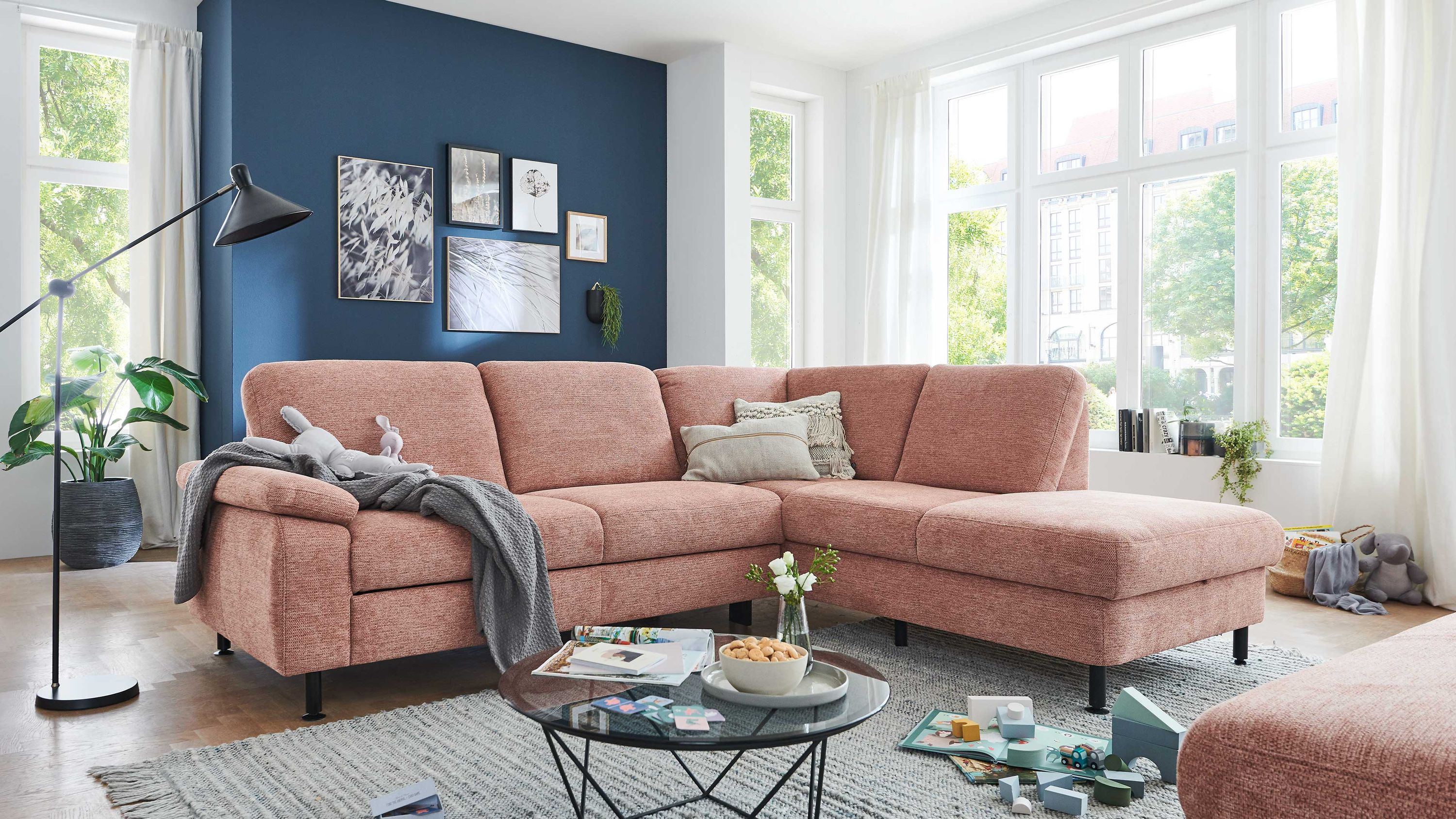 Ecksofa mit sienafarbenem Webstoff und schwarzen Füßen in hellem Wohnzimmer mit großen Fenstern