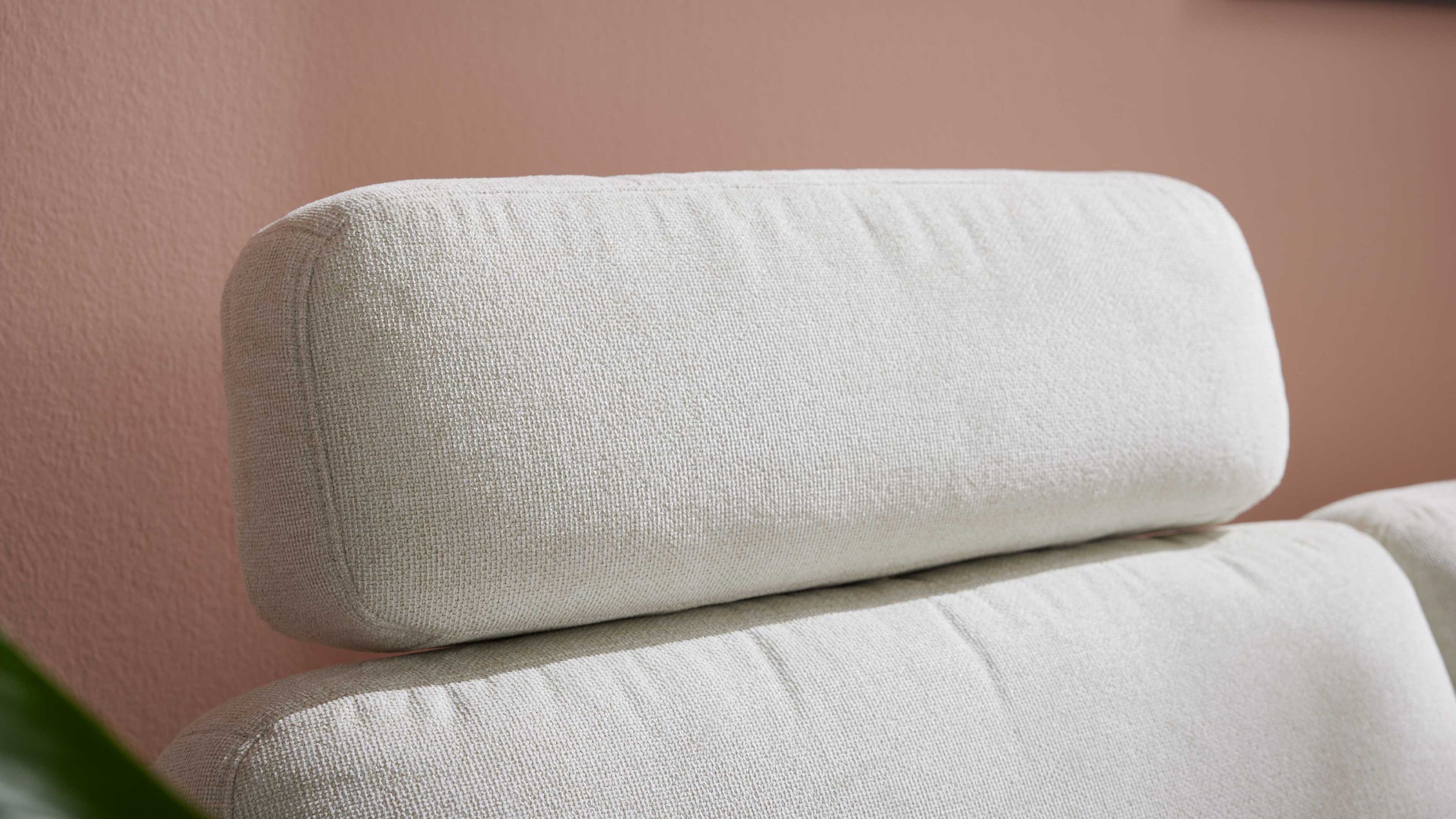 Naturweißes Kopfstützenpolster aus Flachgewebe auf einem Sofa vor rosa Wand