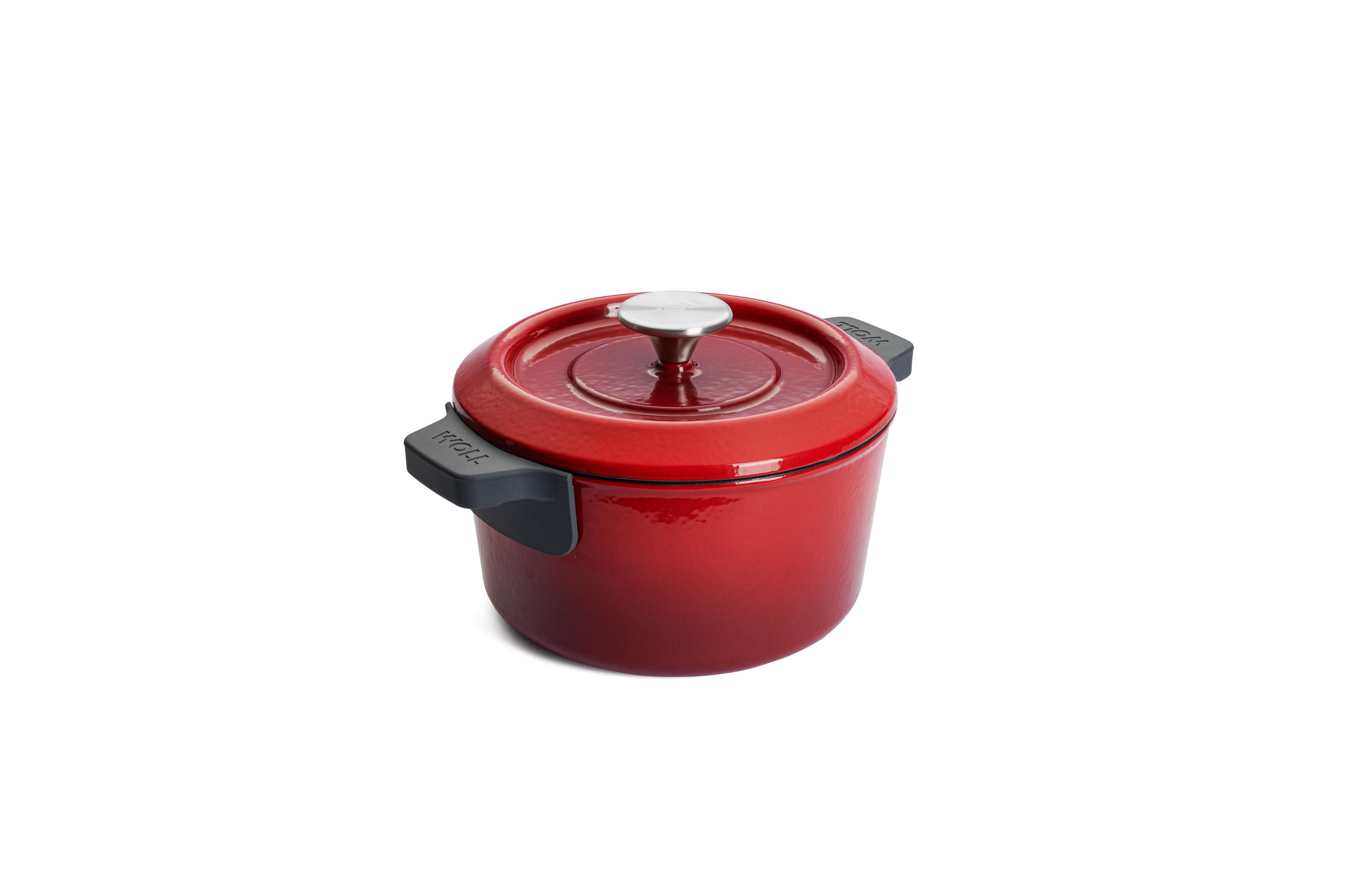 Chilli-rote Kasserolle mit schwarzen Griffen und weißem Deckelknauf leicht erhöht von links auf heller Fläche aufgenommen