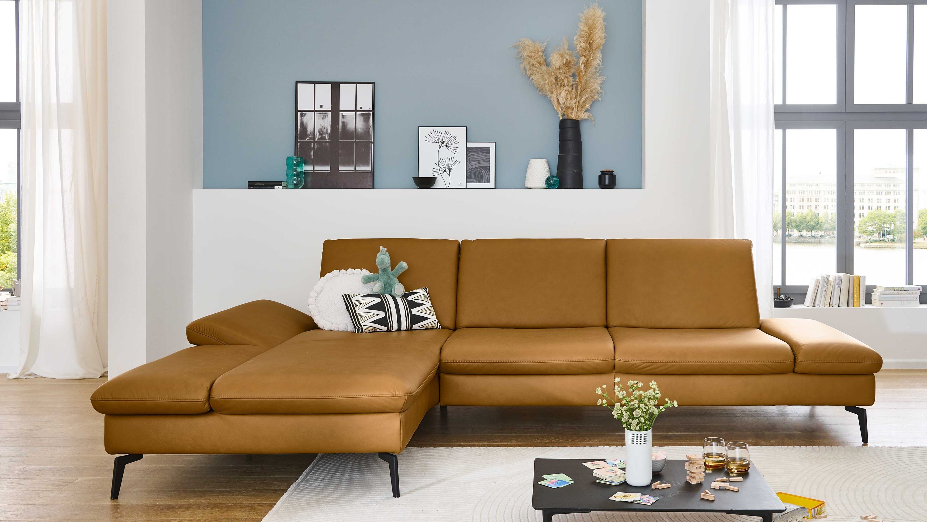 Ecksofa mit kurkumafarbenem Lederbezug und schwarzer Metallfüßen in modernem Wohnzimmer