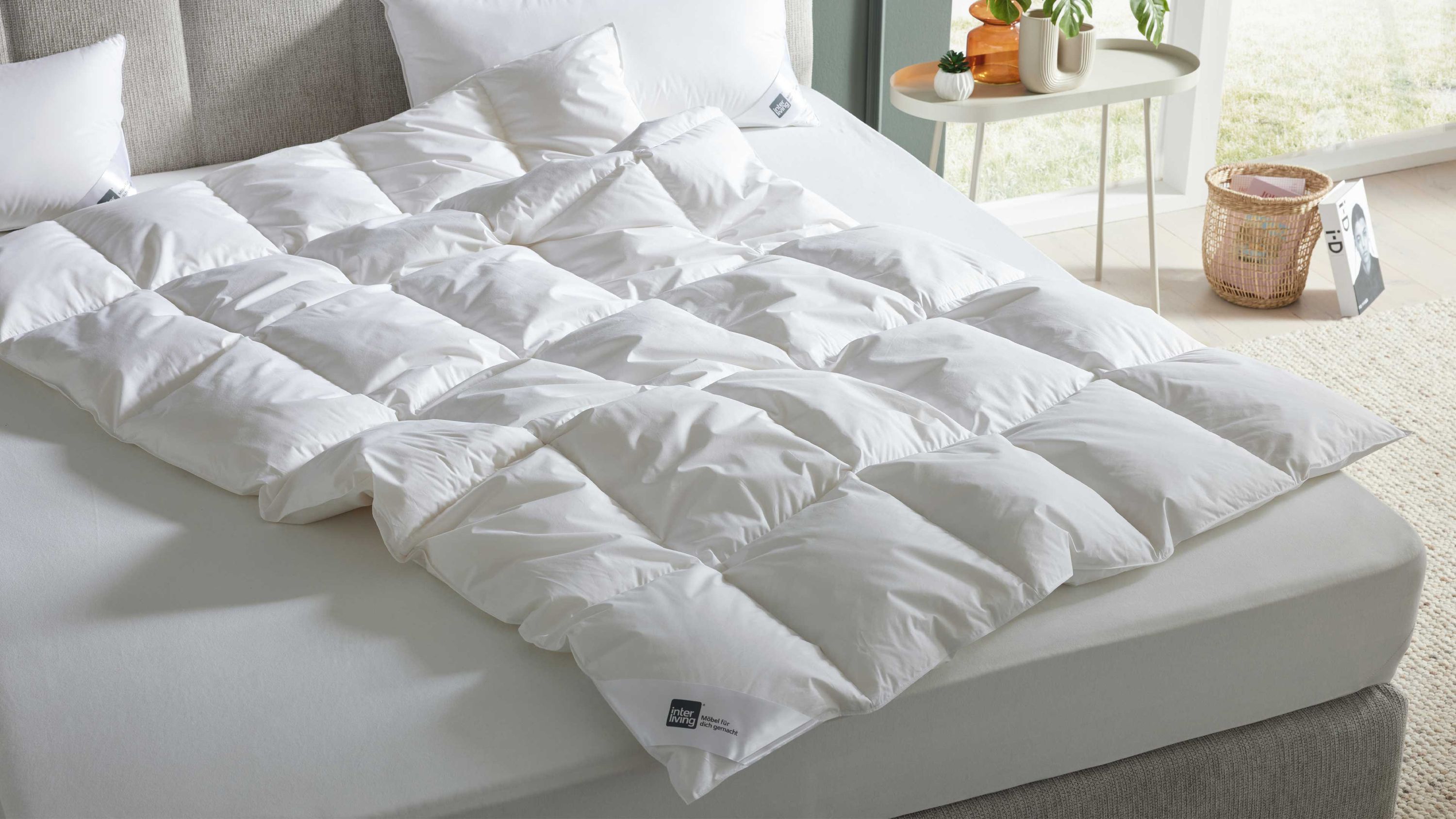 Weiße Cassettendecke mit quadratischen Steppungen auf einem grauen Bett mit weißen Kissen