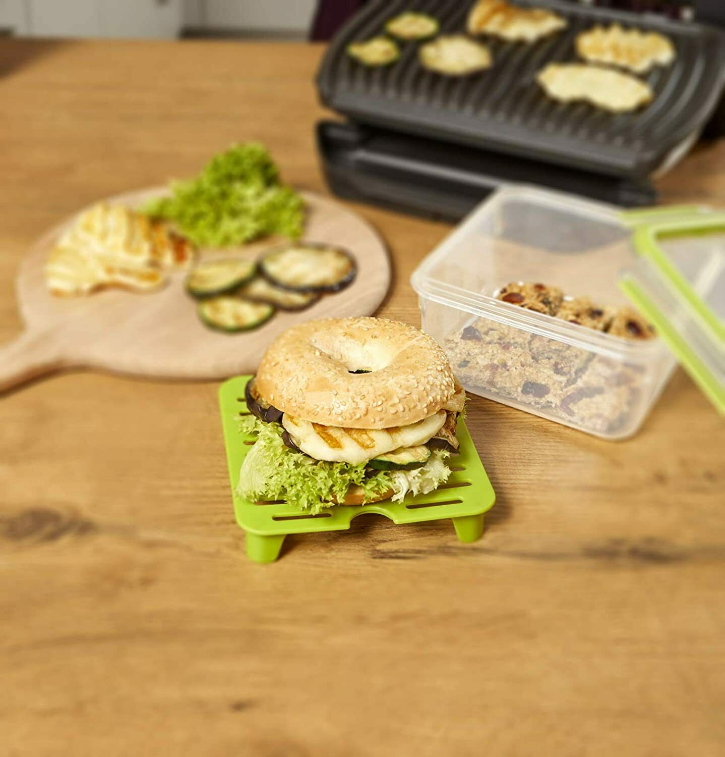 Sandwichbox transparent-grün  auf Holztisch mit belegtem Sandwich  Salat und Dressingbehälter arrangiert