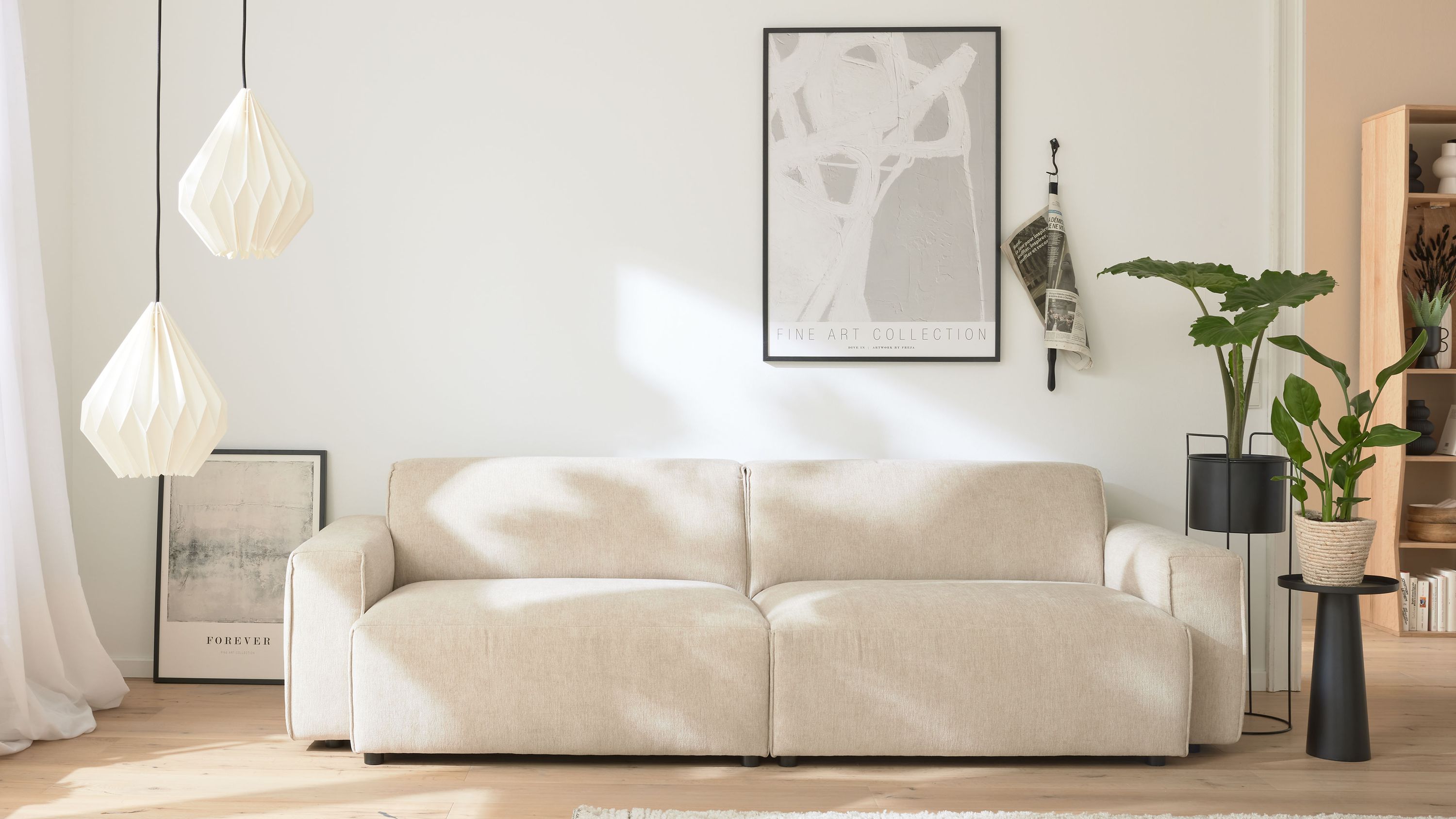25-Sitzer Sofa mit champagnerfarbenem Bezug in modernem Wohnzimmer mit Pflanzen und Wandbildern