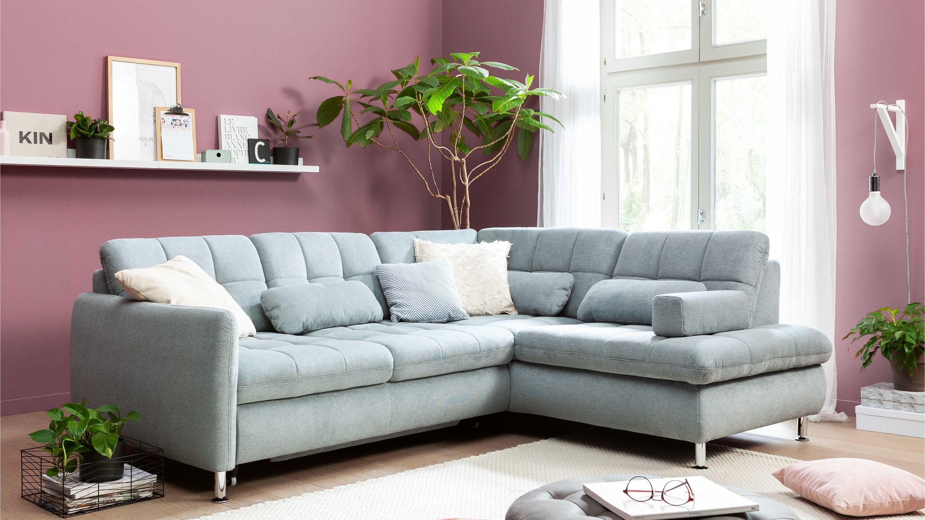 Ecksofa in stahlgrauer Chenille mit Chromfüßen Ecksofa in stahlgrauer Chenille mit Chromfüßen und mehreren Kissen in hellem Wohnzimmer