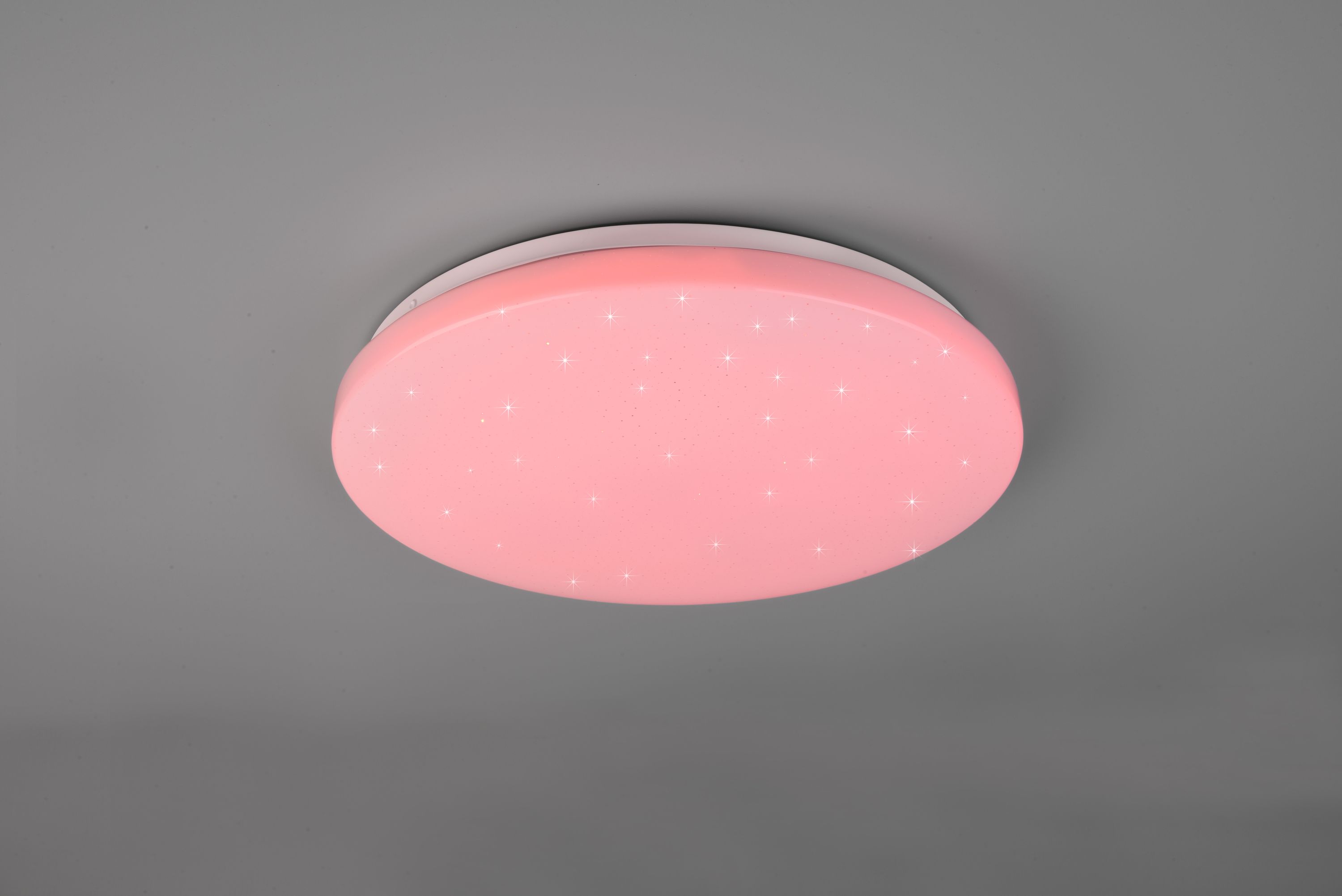 Runde Deckenleuchte aus weißem Kunststoff mit flachem Design  leuchtet pink; leicht schräg von unten fotografiert