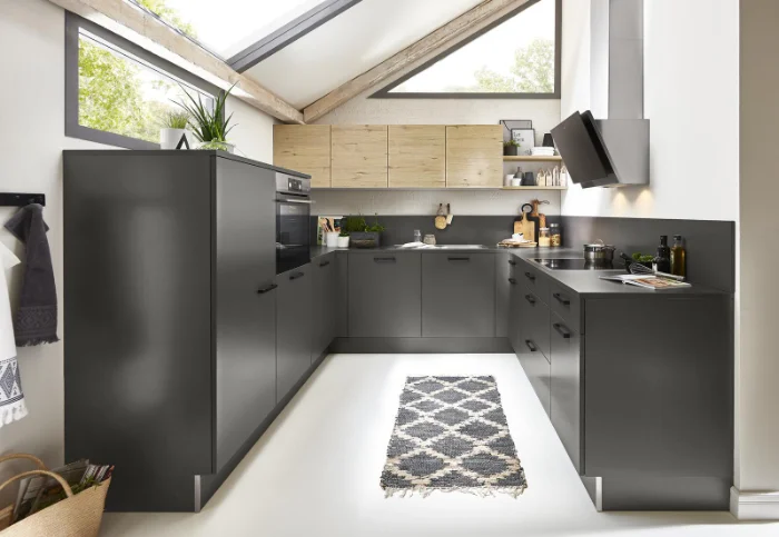 U-förmige Designküche in Anthrazit mit Holzoberschränken unter Dachschrägen, ausgestattet mit Backofen, Kochfeld und Dachfenstern.