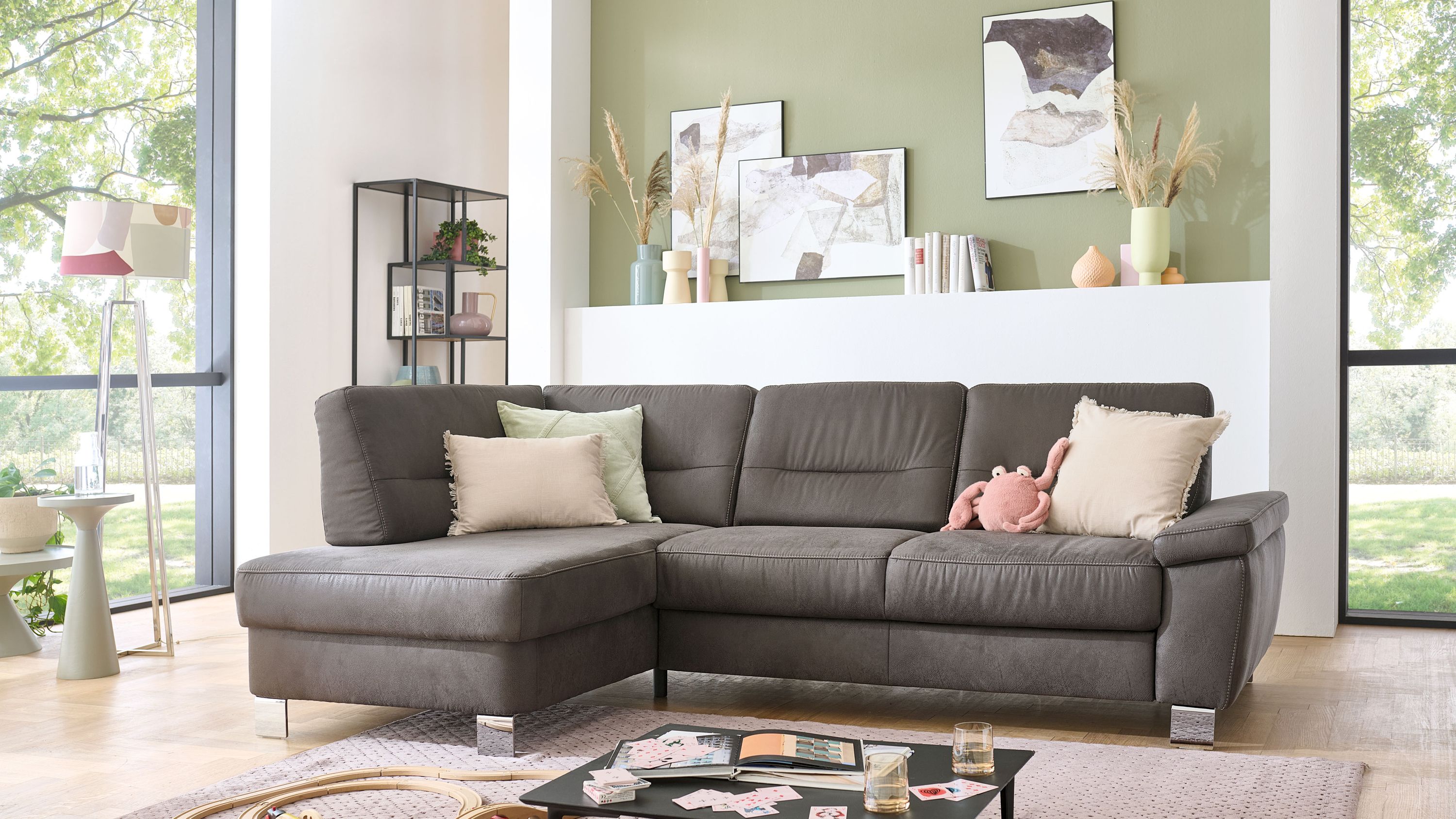 Anthrazitfarbenes Ecksofa mit Mikrofaserbezug Metallfüßen und mehreren Kissen in hellem Wohnzimmer