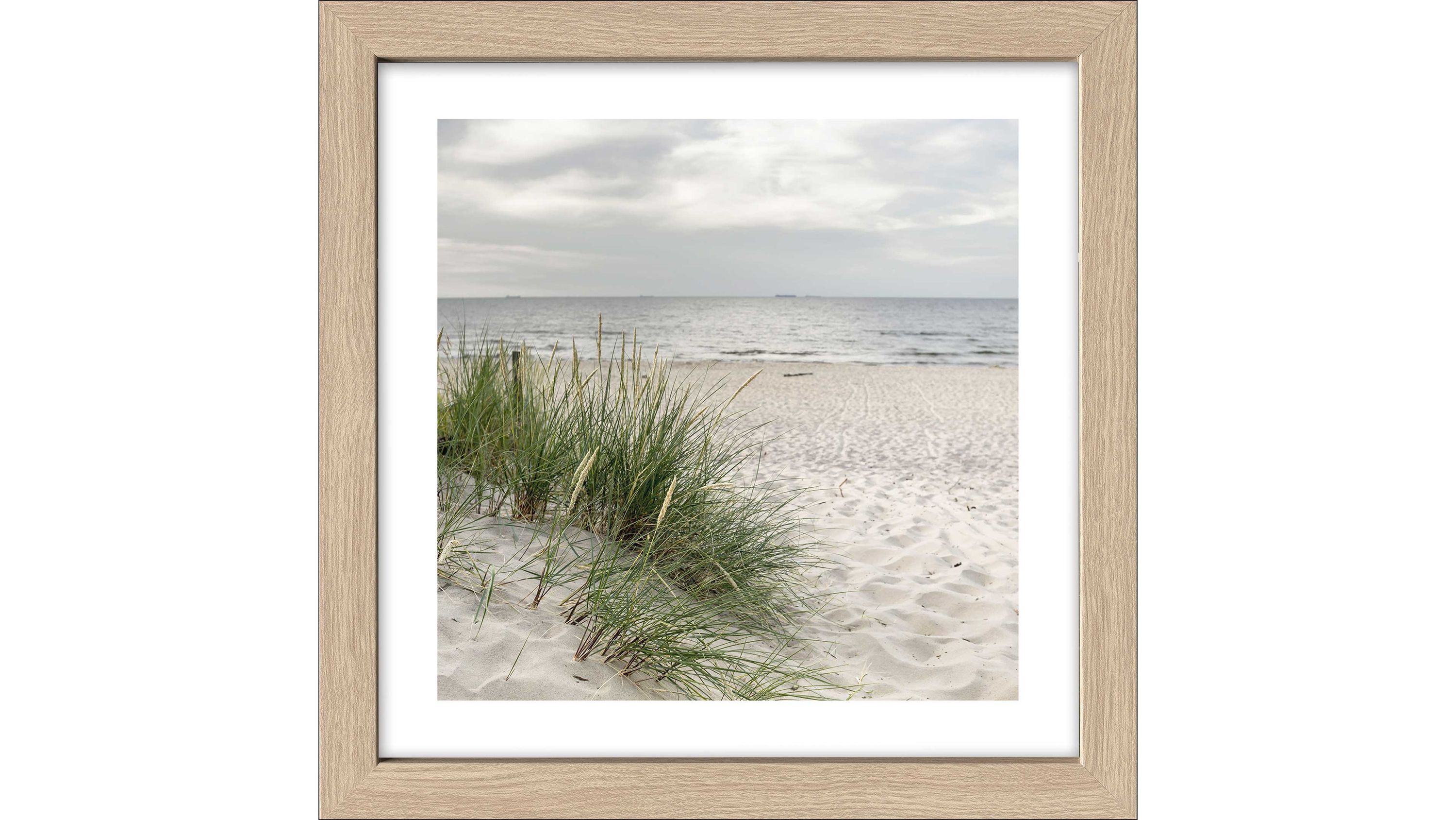 Kunstdruck eines Strandes mit Sand Gras und Meer in einem hellen Holzrahmen
