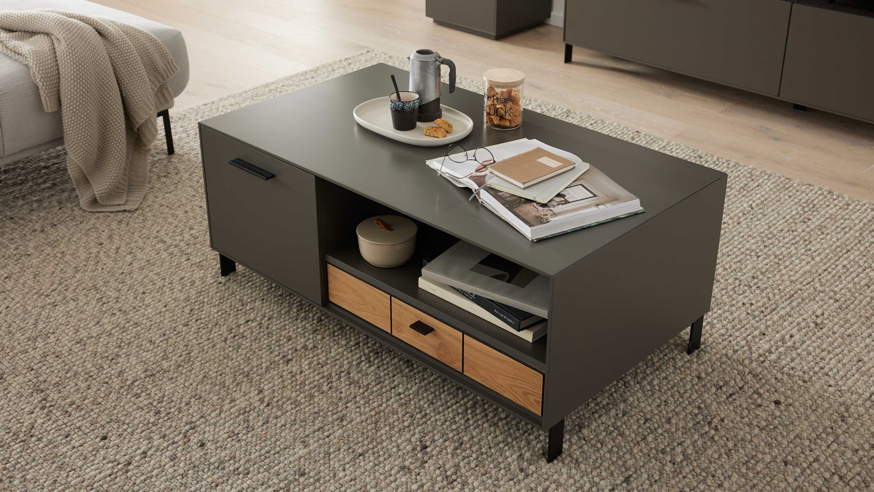 Couchtisch mit Türen und Schublade in Grau und Holzfarben Rechteckiger Couchtisch mit zwei Türen und einer Schublade in grau und Holzfarben auf Teppich