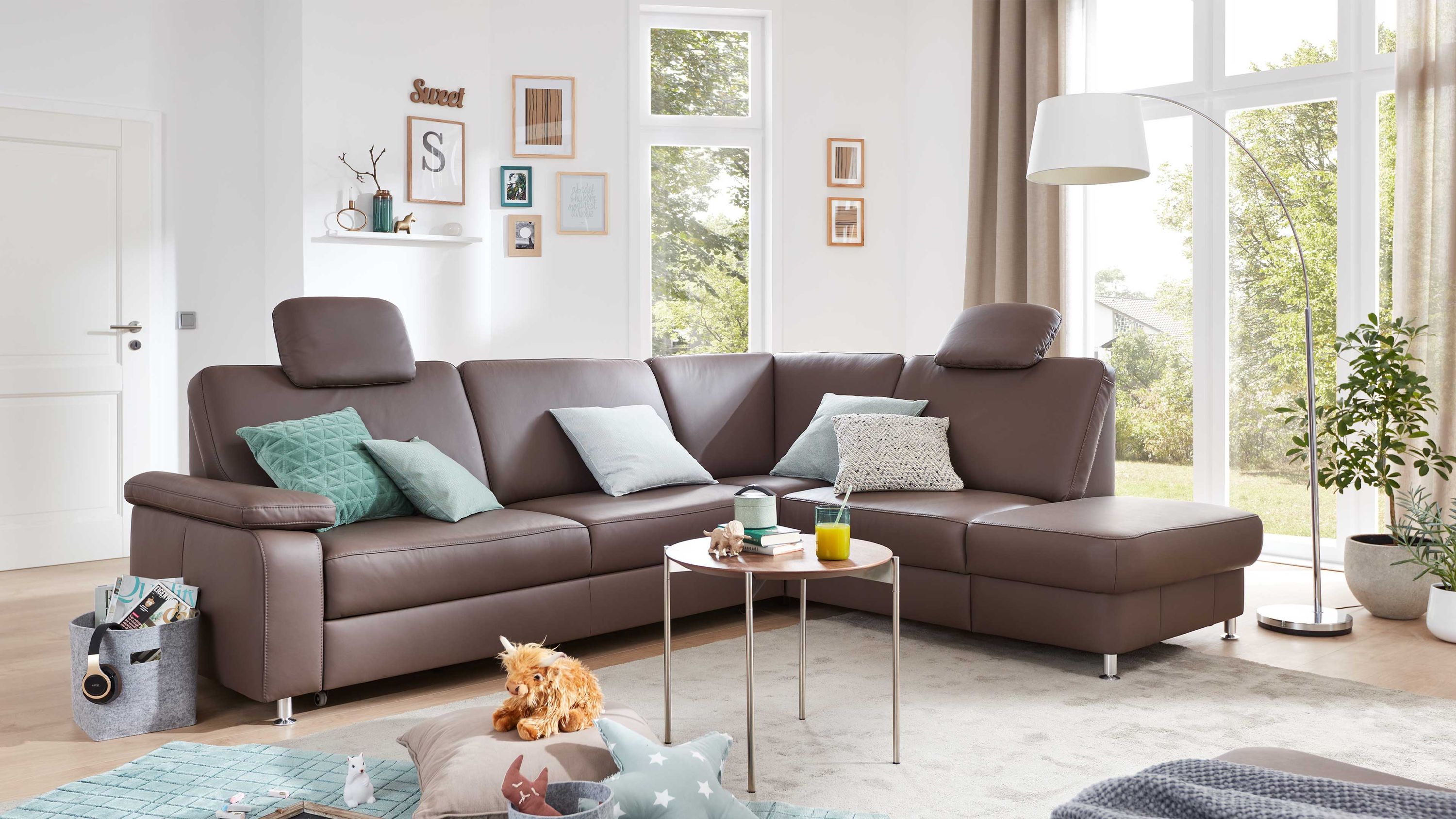 Ecksofa mit moccafarbenem Lederbezug und Metallfüßen in modernem Wohnzimmer mit Kissen
