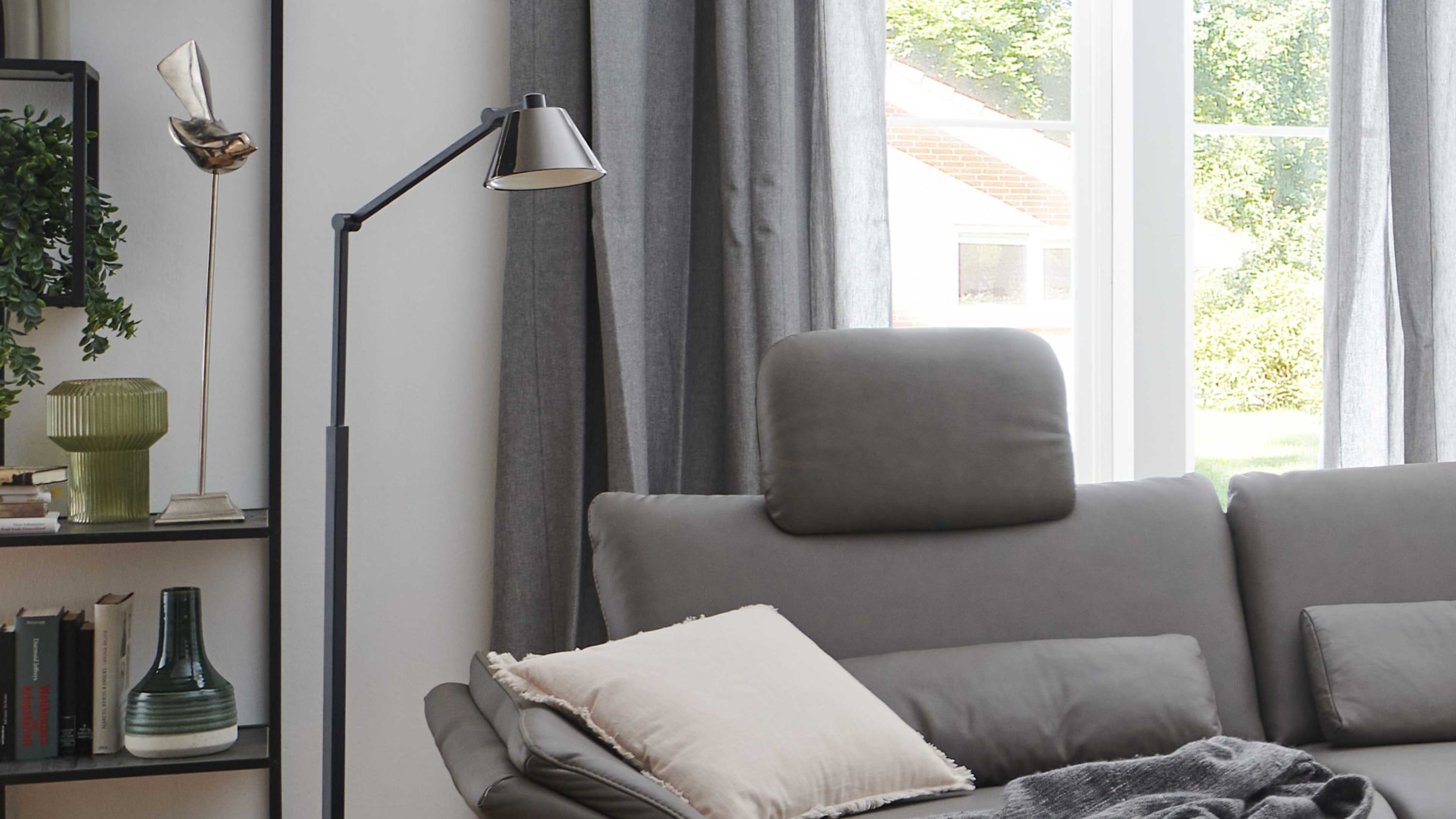 Kopfstütze auf Sofa in steingrau Steingraue Kopfstütze auf grauem Sofa vor Fenster mit grauen Vorhängen