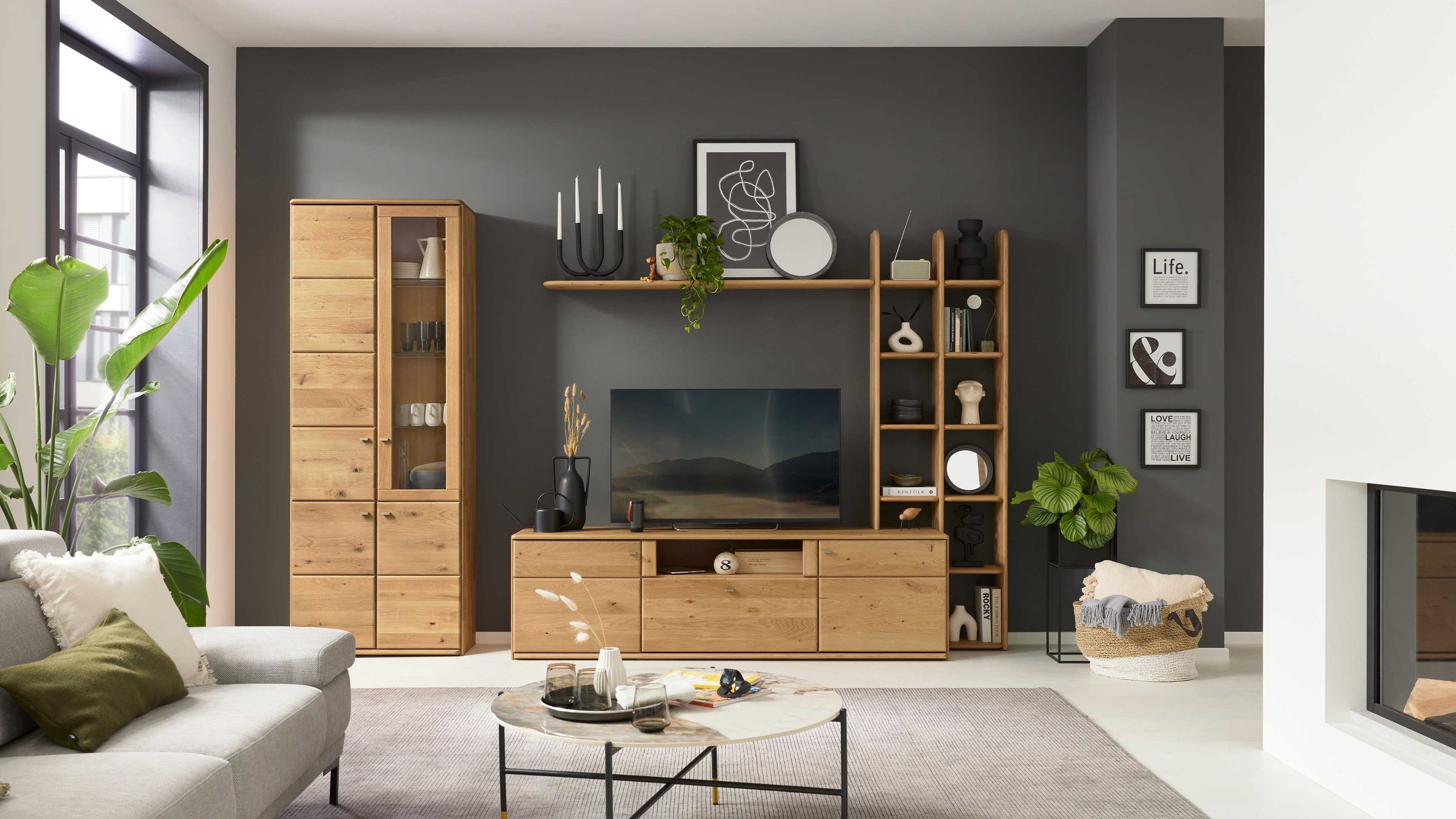 Vierteilige Wohnwand aus hellem Holz Vierteilige Wohnwand aus hellem Holz mit Vitrine Regal TV-Board und Wandregal vor dunkelgrauer Wand