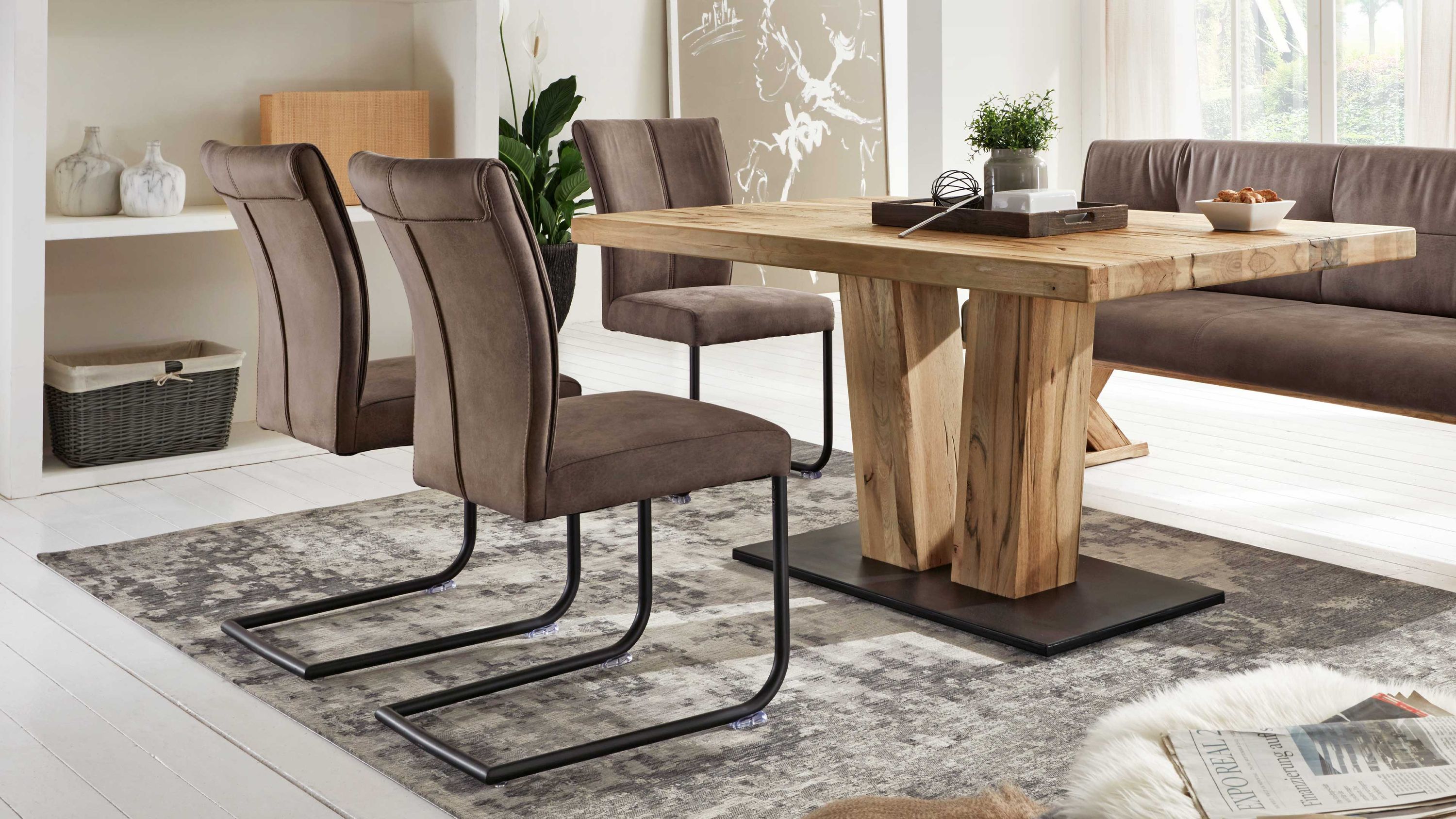 Vier schwingstühle mit steinfarbener mikrofaser und schwarzem metallgestell um einen holztisch in einem esszimmer
