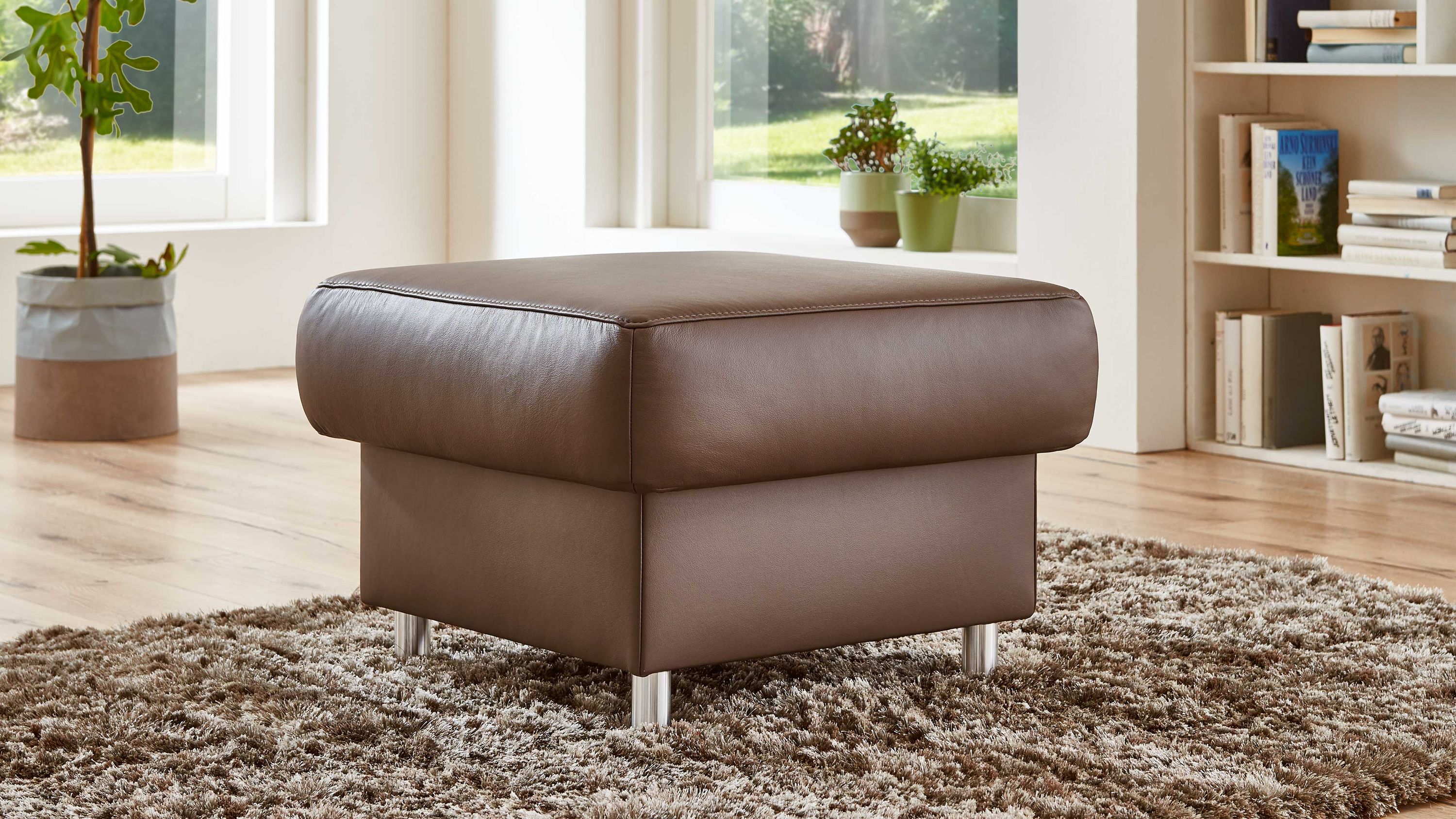 Quadratischer Polsterhocker mit moccafarbenem Bezug und Metallfüßen auf Teppich in hellem Raum