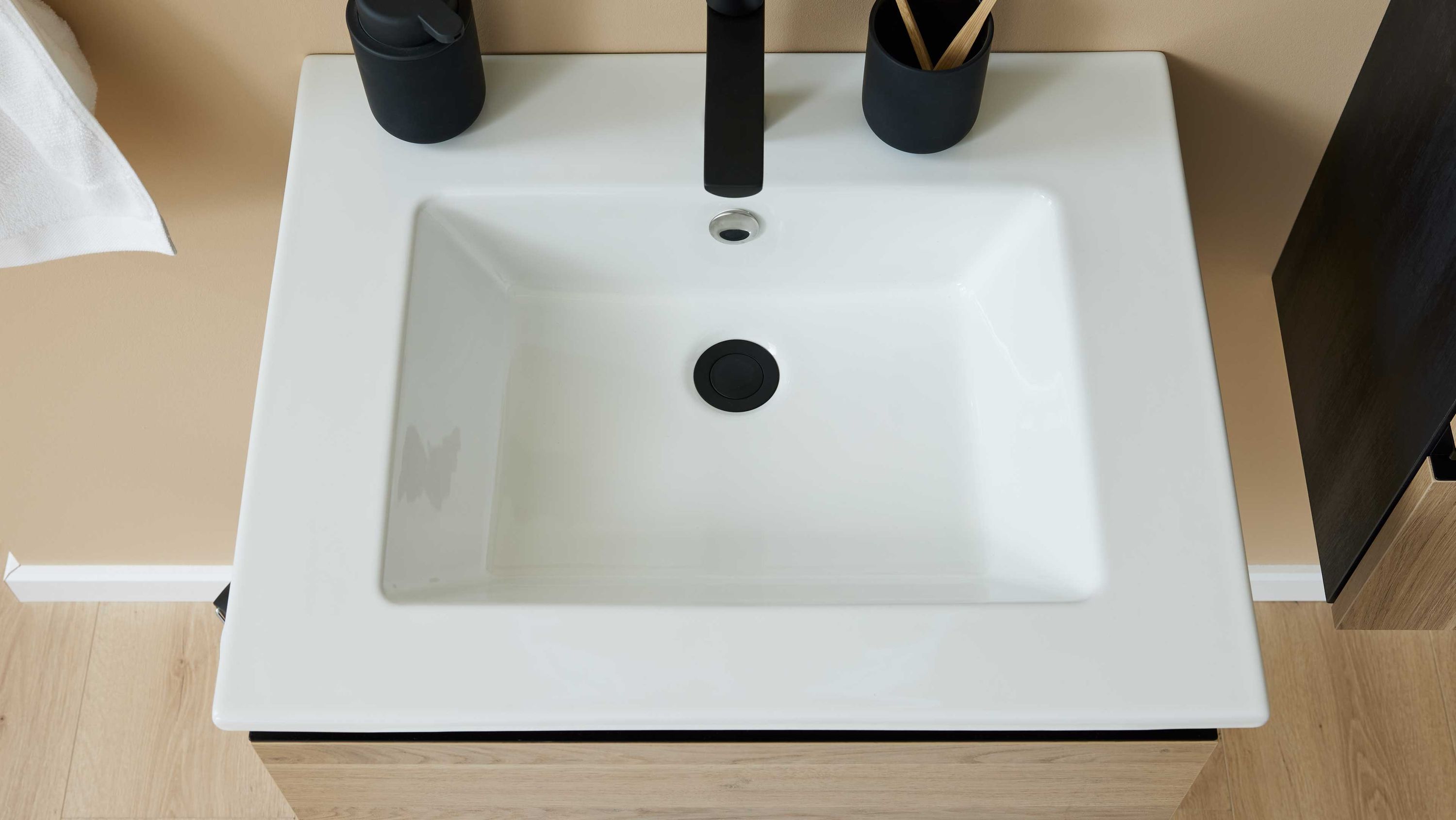 Rechteckiger weißer Waschtisch aus Keramik mit schwarzem Wasserhahn und schwarzen Accessoires