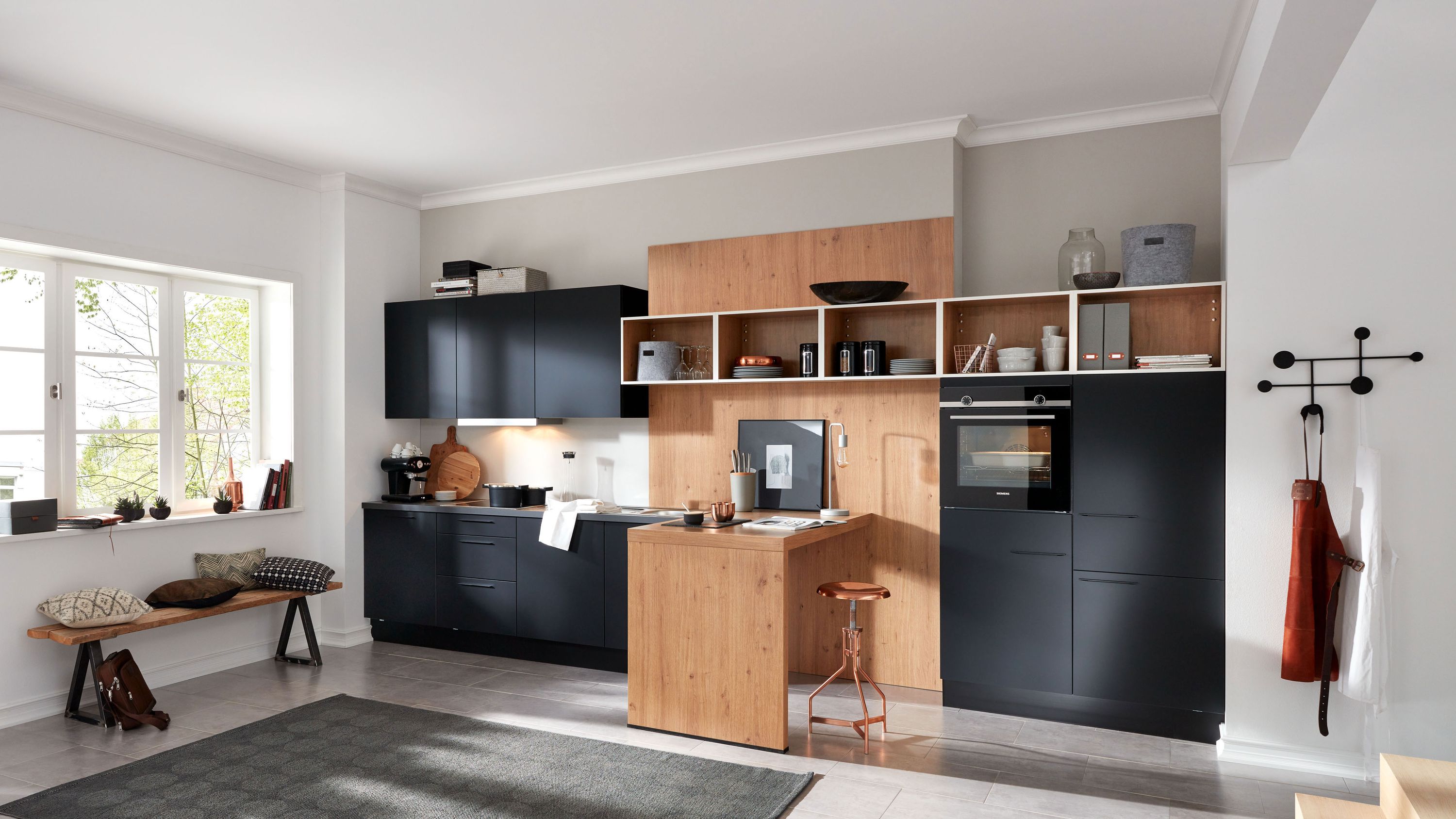 Schwarze Küche mit Holzinsel und Fensterbank Schwarze und Holzfronten Insel offene Regale Einbaugeräte Fensterbank mit Kissen Wandhaken mit Textilien.