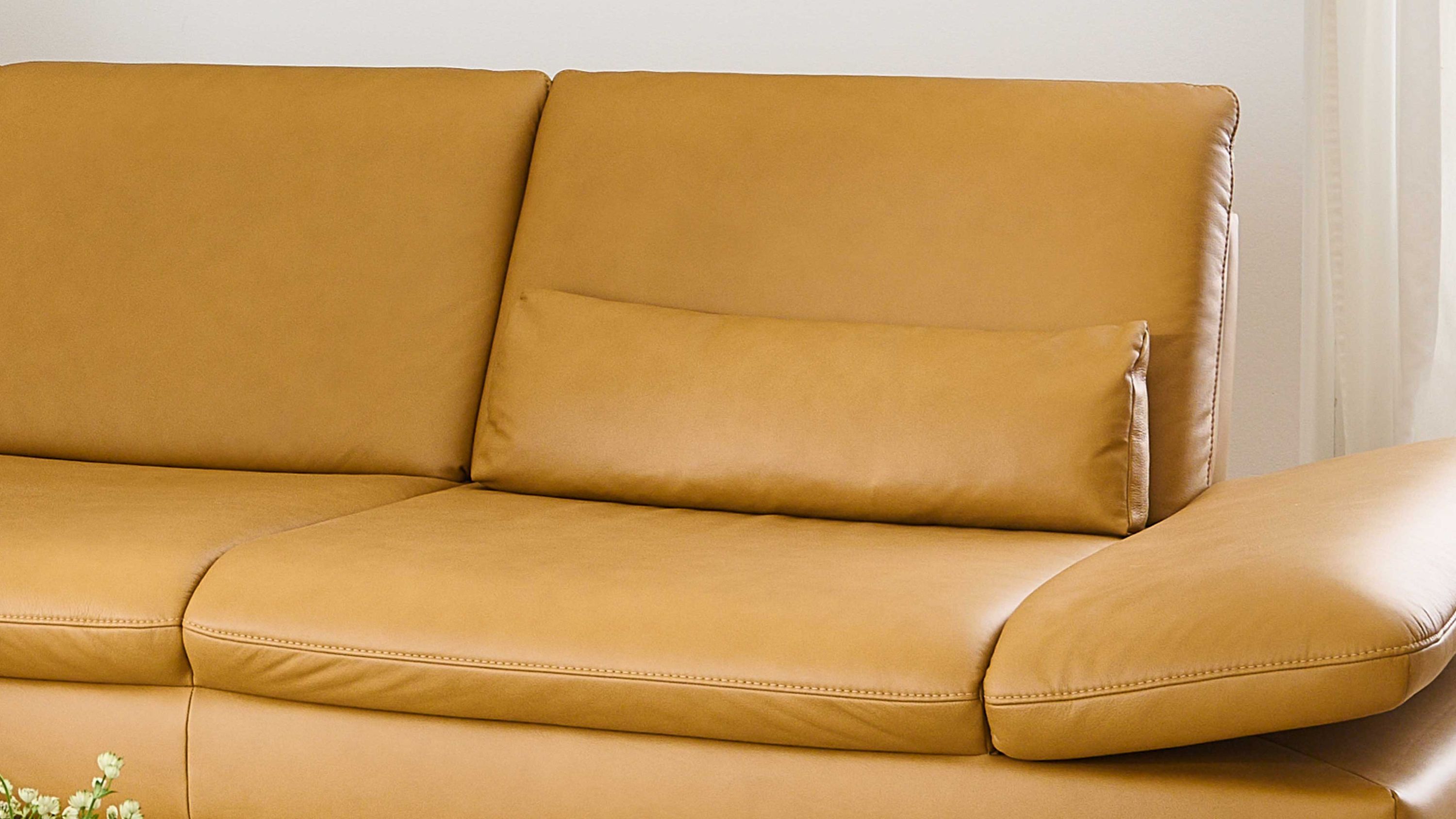 Rechte Seite eines gelblichen Ledersofas mit rechteckigem Nierenkissen
