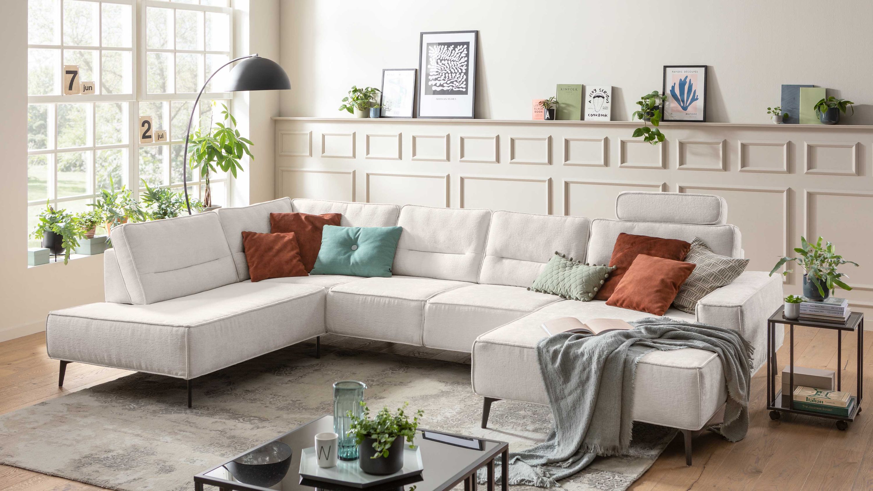 Naturweiße Couchlandschaft mit schwarzer Metallfüßen und bunten Kissen in hellem Wohnzimmer
