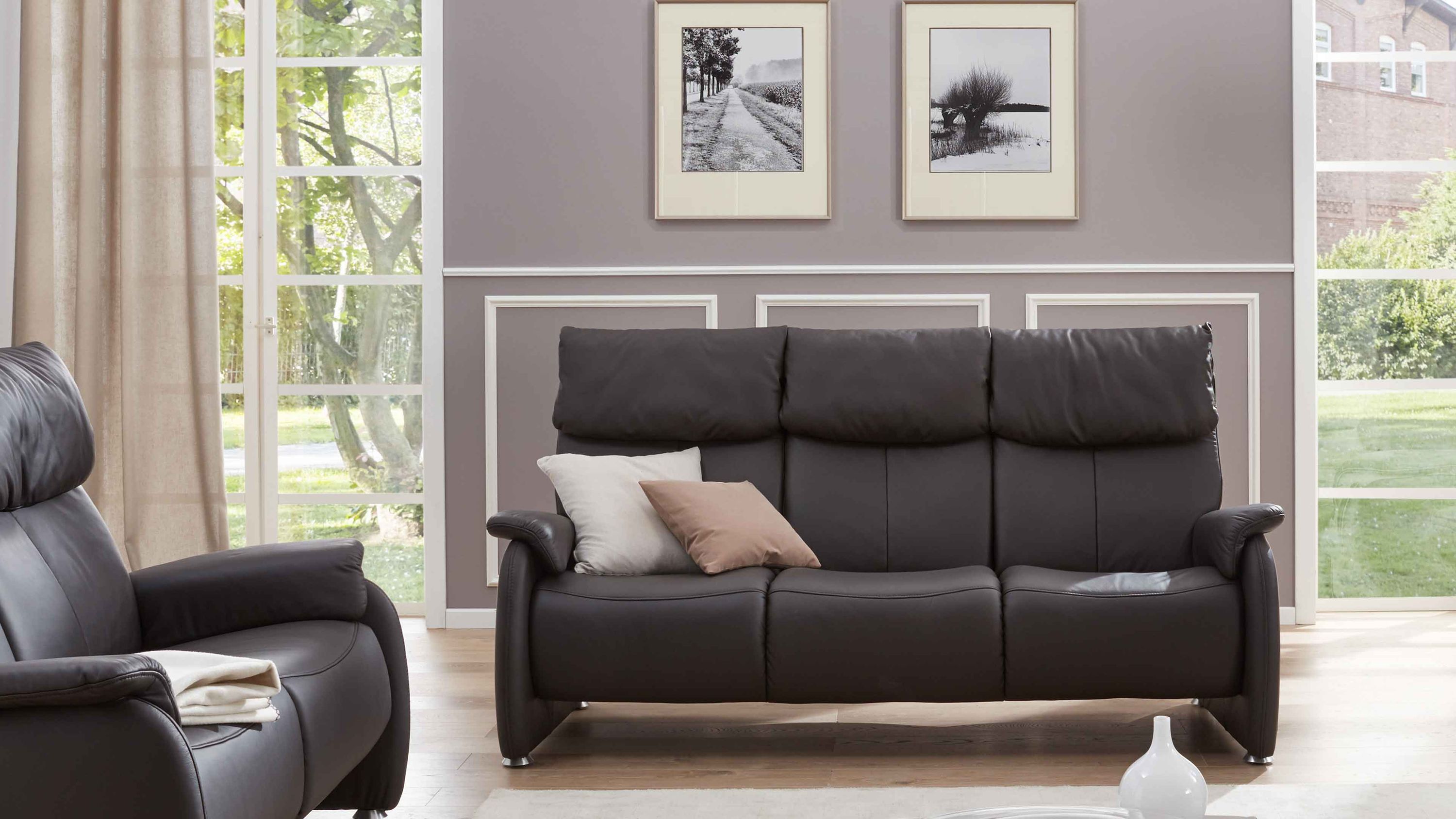 Dreisitziges Sofa in dunkelbraunem Leder mit gepolsterten Armlehnen und Rückenlehnen in modernem Wohnzimmer