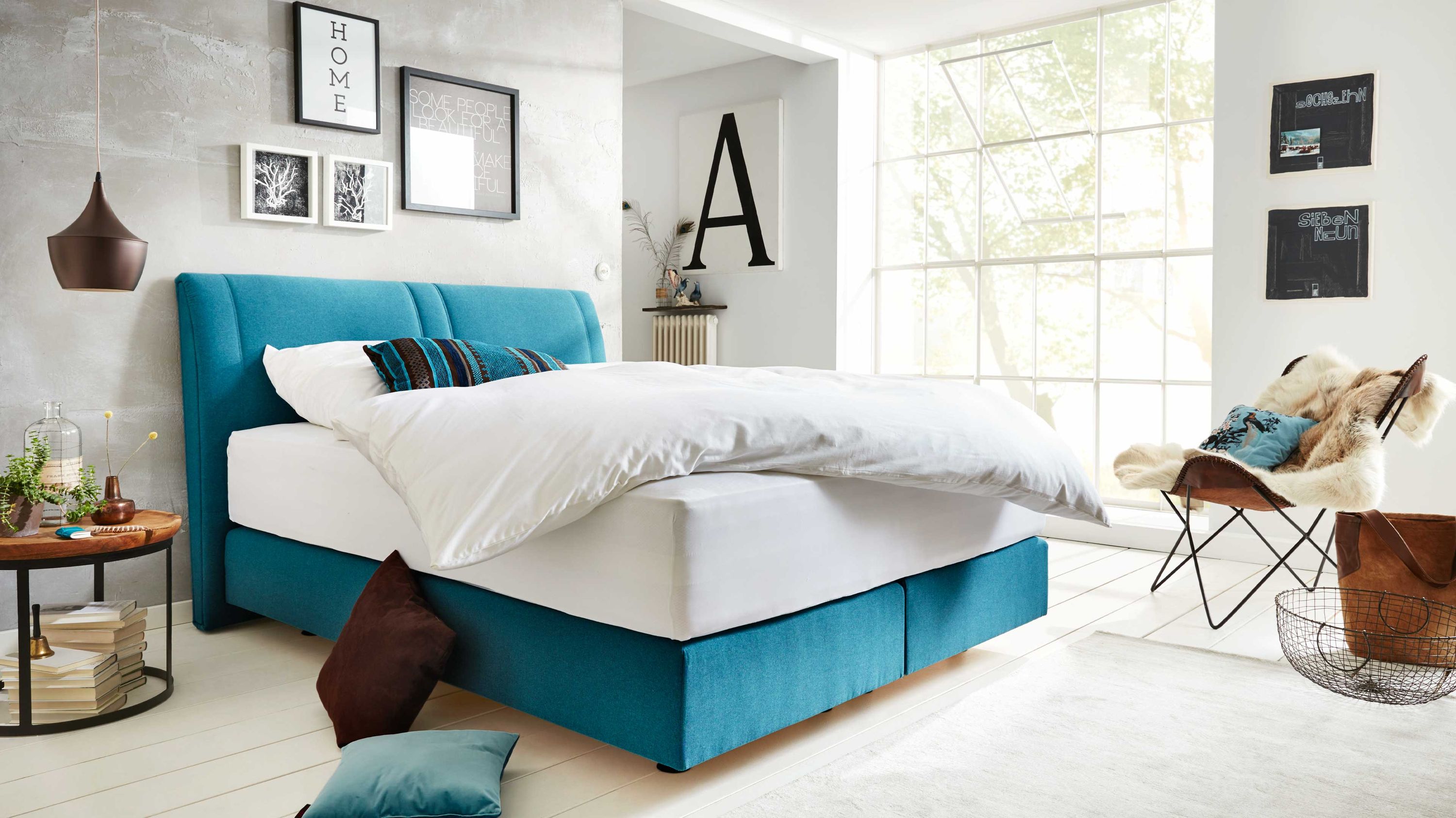 Boxspringbett mit gepolstertem Kopfteil in petrolfarbenem Stoff in modernem Schlafzimmer