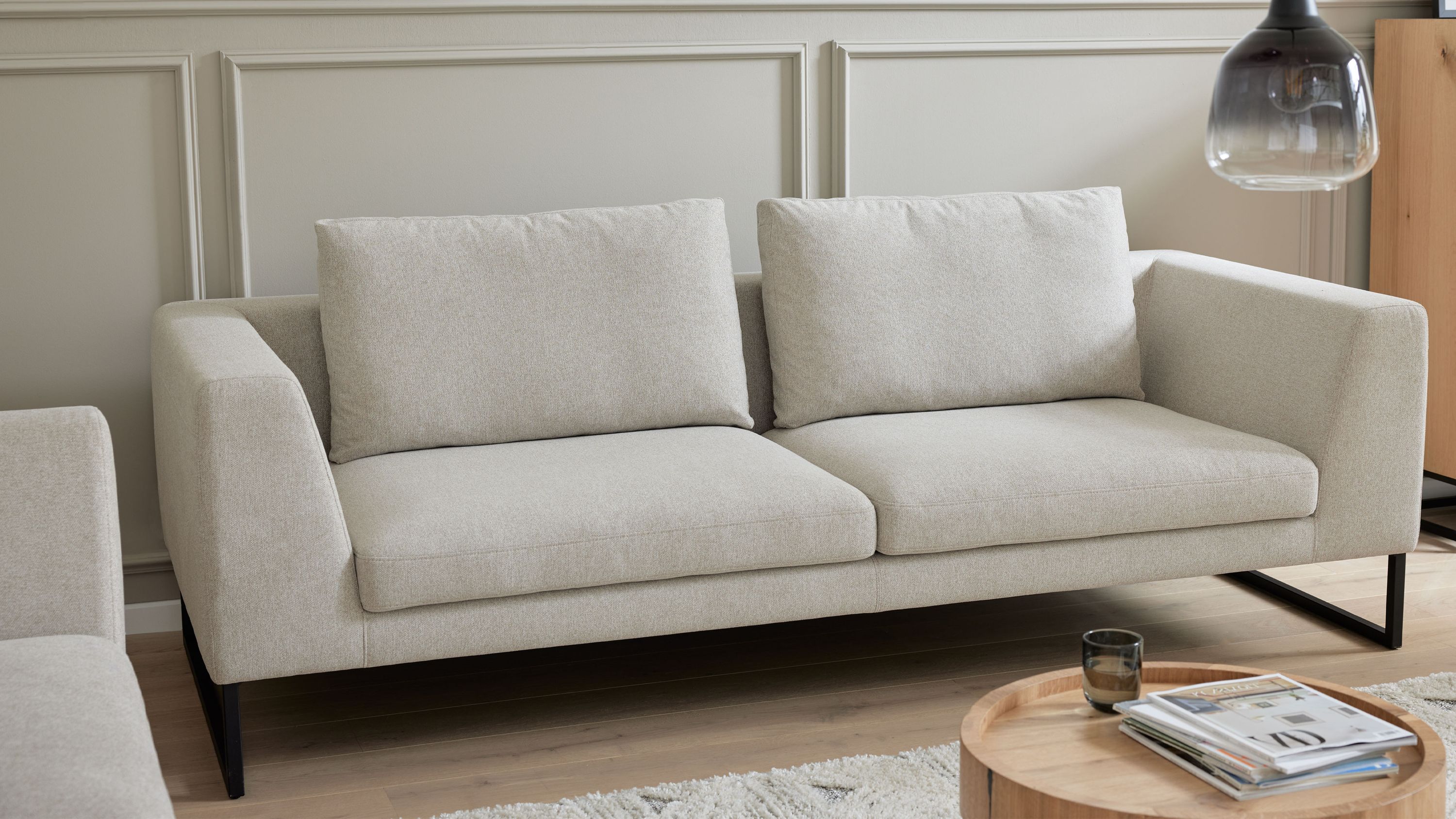 Sandfarbenes Sofa mit zwei Sitz- und Rückenkissen und schwarzen Kufenfüßen in modernem Wohnzimmer