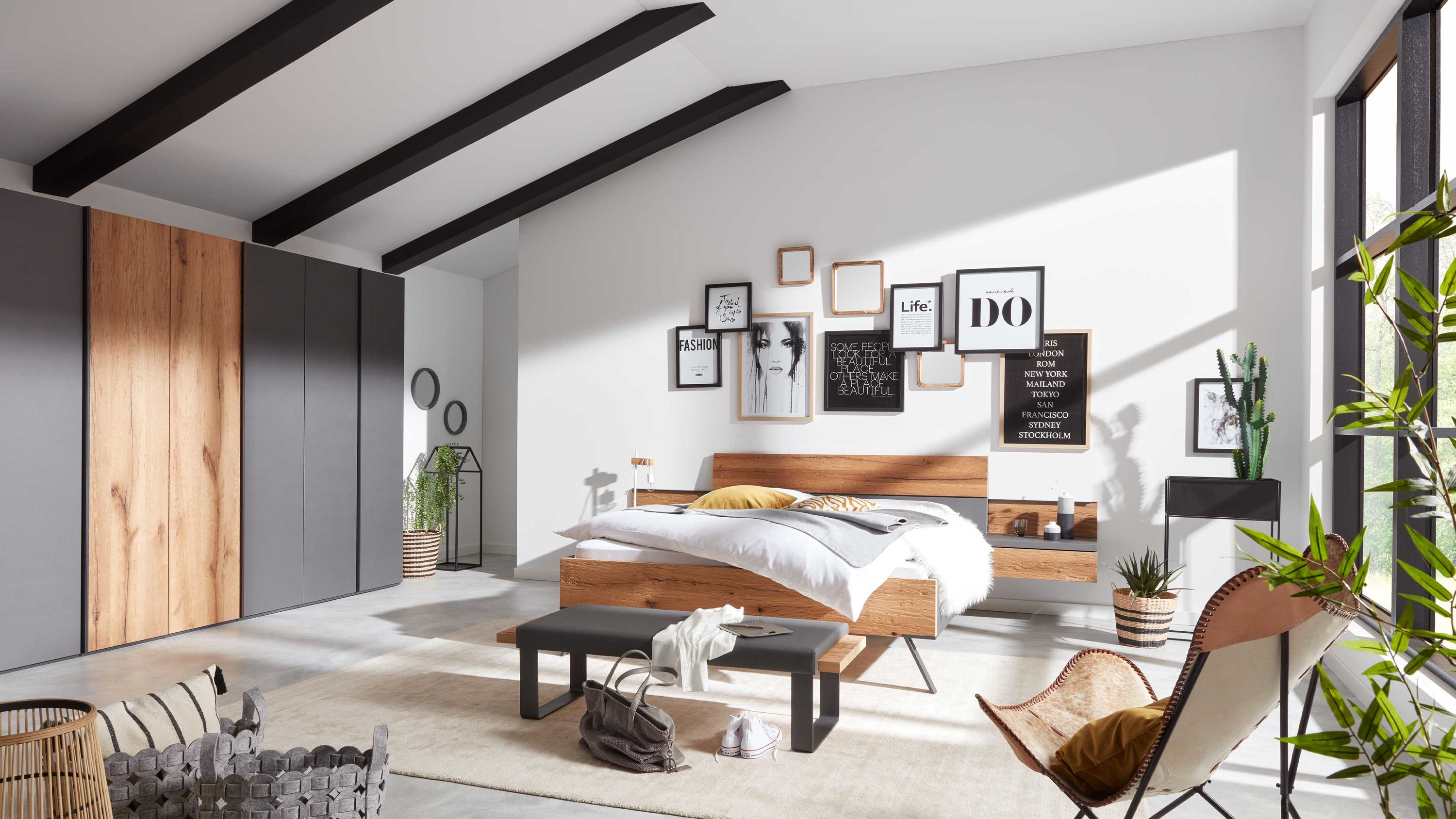 Schlafzimmer mit Bett und Kleiderschrank in Holz und Graphit Schlafzimmer mit Bett großem Kleiderschrank und Sitzbank in Holz- und dunkler Farbe