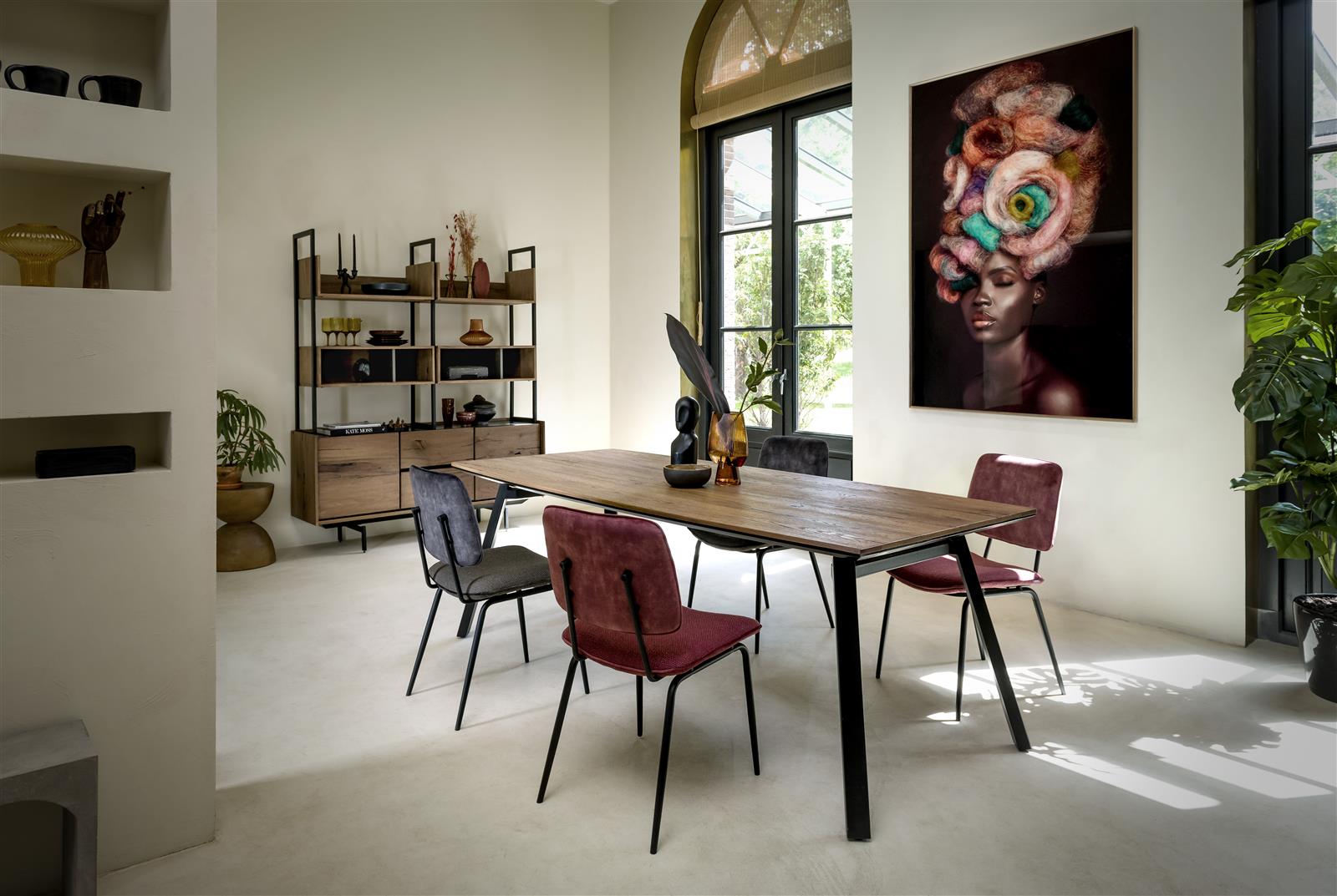 Esszimmer mit Ausziehtisch aus Eiche vier bunten Stühlen Fenster Bücherregal und Wandbild modern eingerichtet