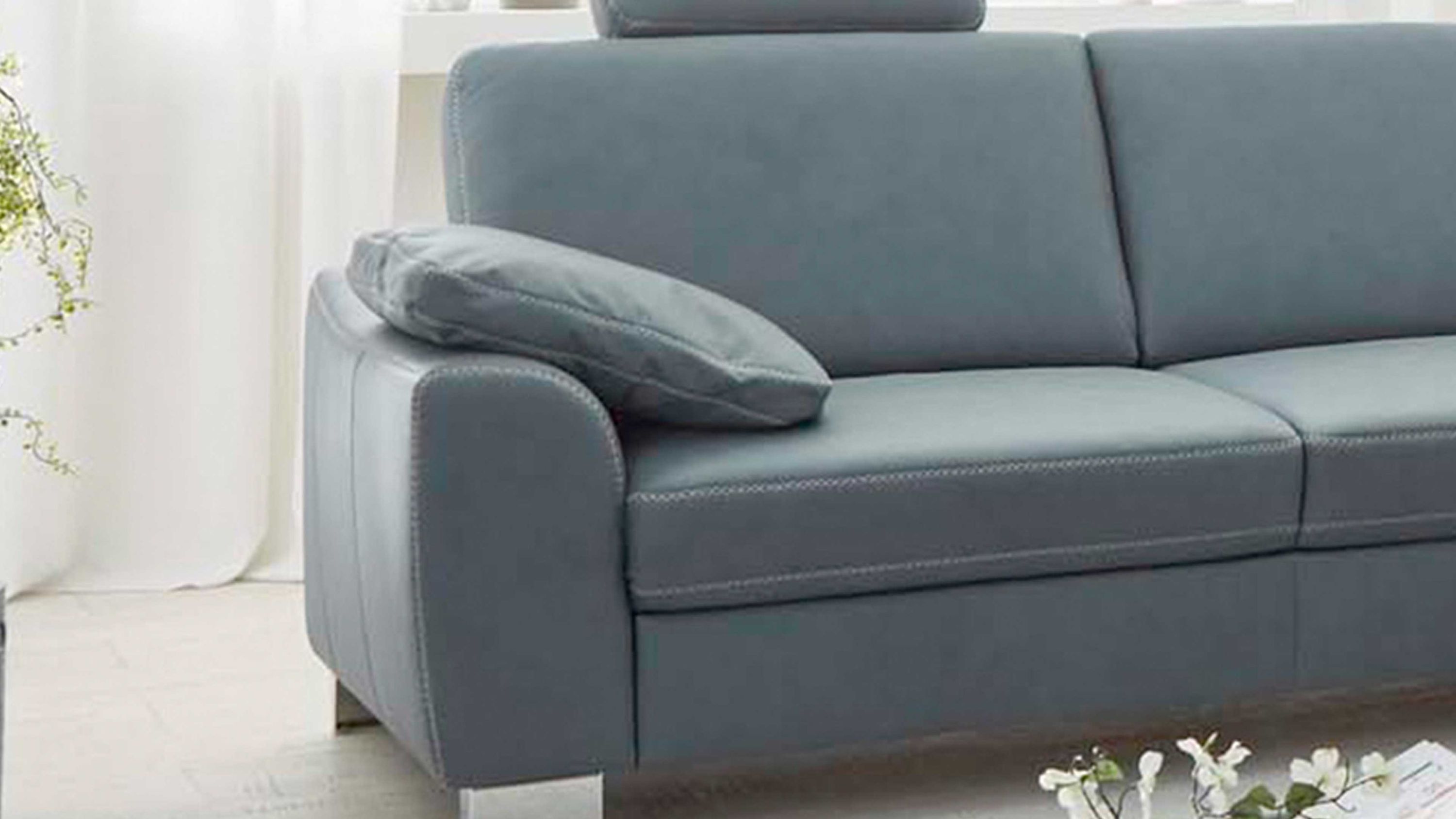 Rechteckiges Kissen in stahlgrauer Farbe auf der Armlehne eines grauen Sofas