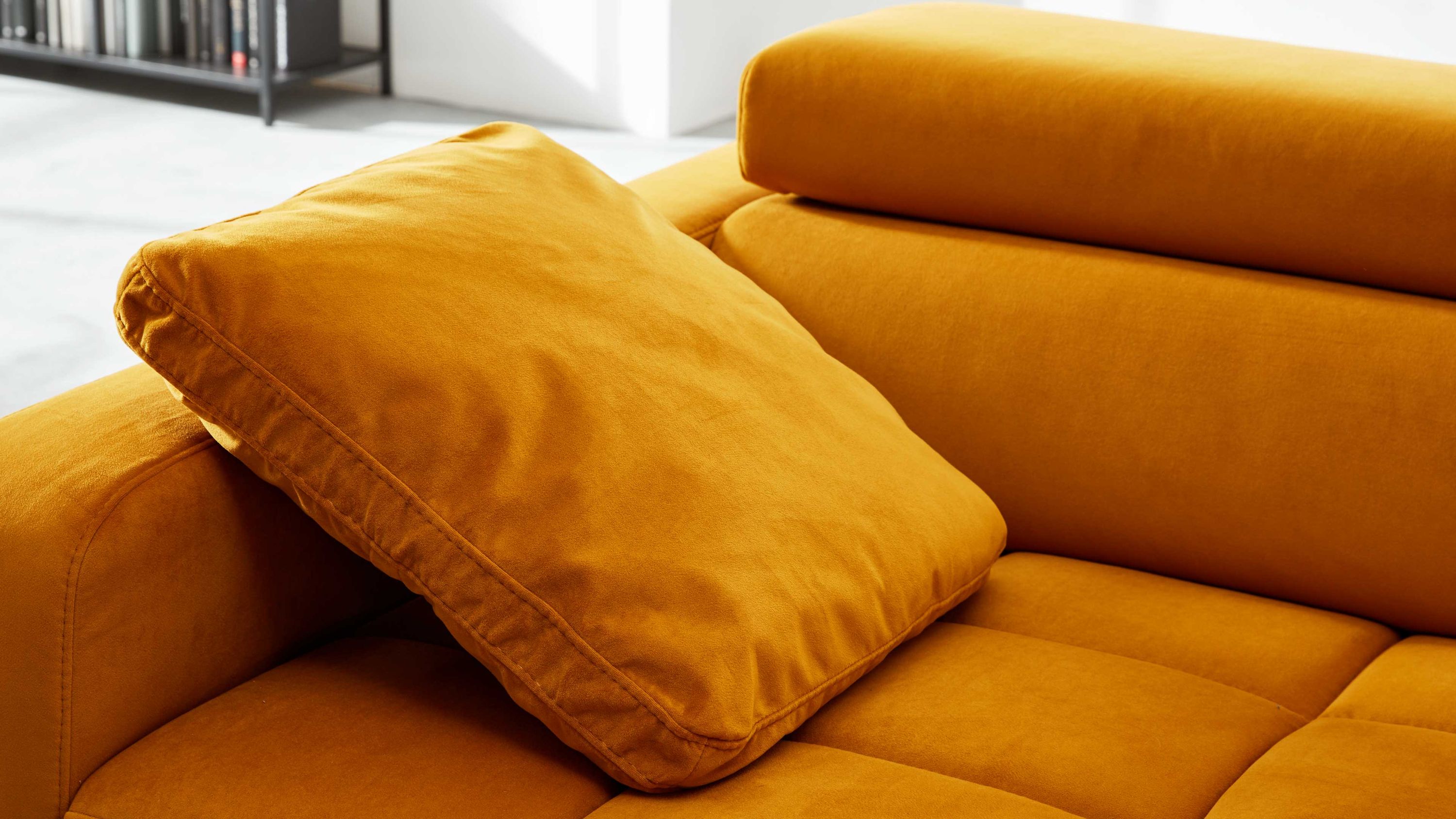 Quadratisches Armlehnkissen in curryfarben auf einem Sofa mit gepolsterten Armlehnen und Rückenlehnen
