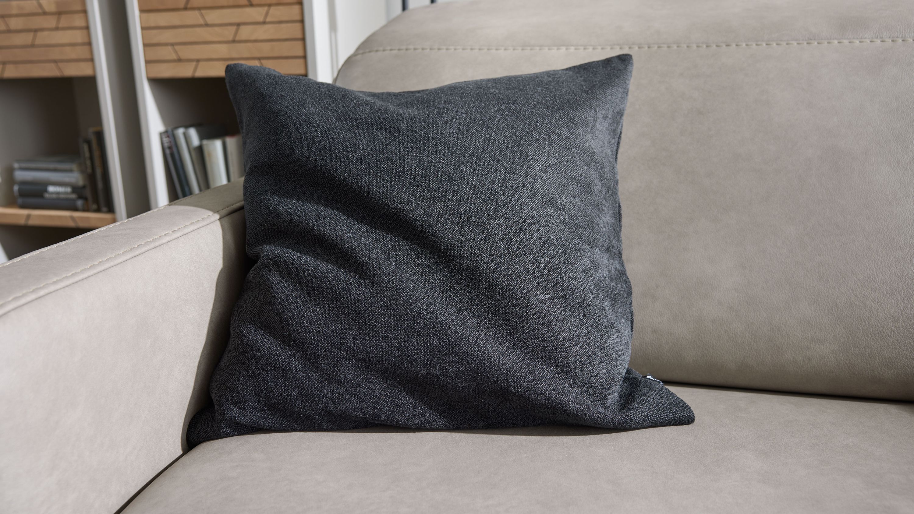 Schwarzes Chenillekissen auf Sofa Quadratisches Kissen mit schwarzer Chenillehülle auf hellgrauem Sofa