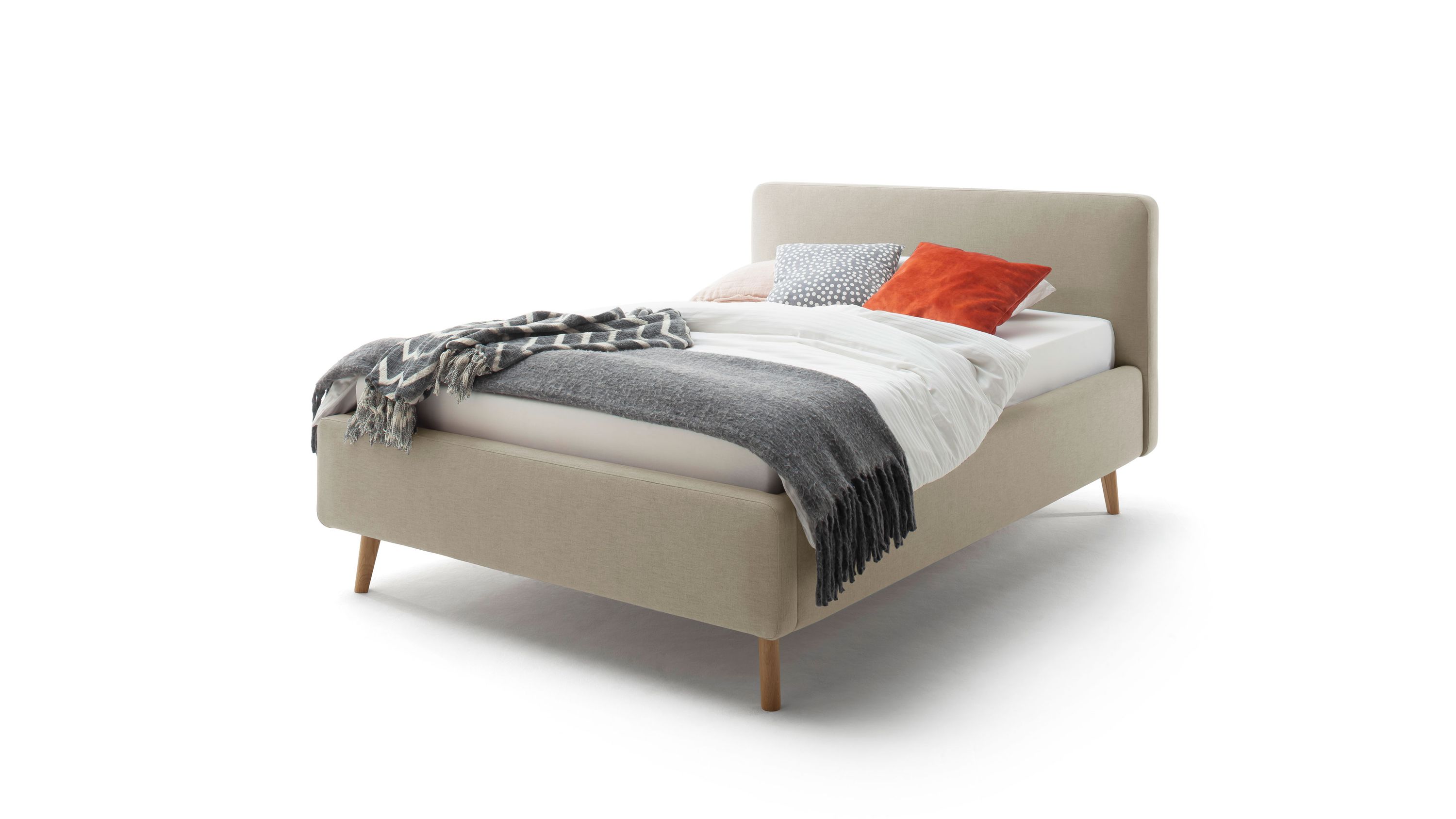 Polsterbettgestell mit Holzfüßen in Taupe Polsterbettgestell in taupe mit hohem Kopfteil und Holzfüßen mit Decken und Kissen belegt