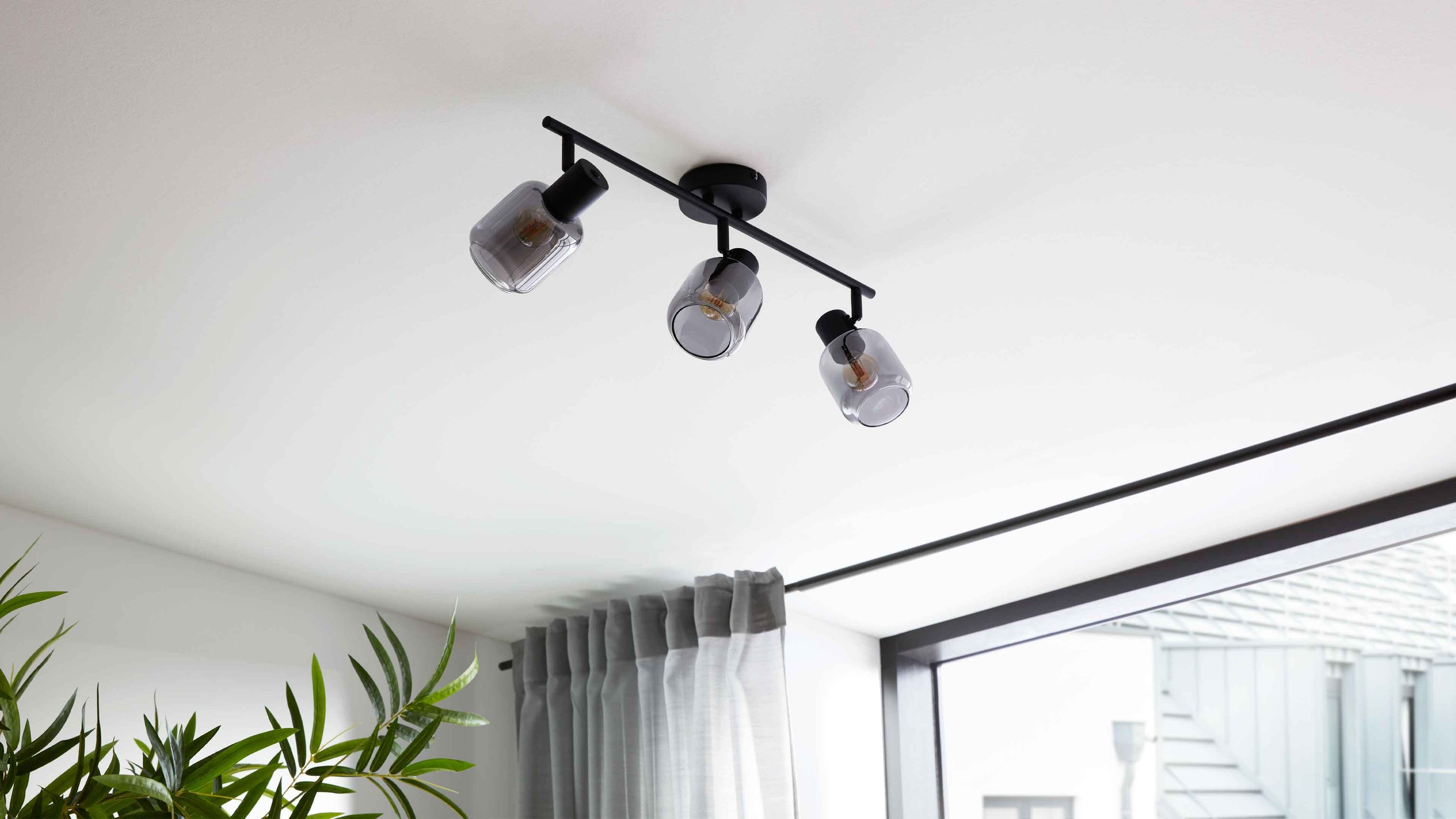 Deckenleuchte mit drei Rauchglasschirmen und mattschwarzem Gestell Deckenleuchte mit drei runden Rauchglasschirmen und mattschwarzem Gestell an der Decke