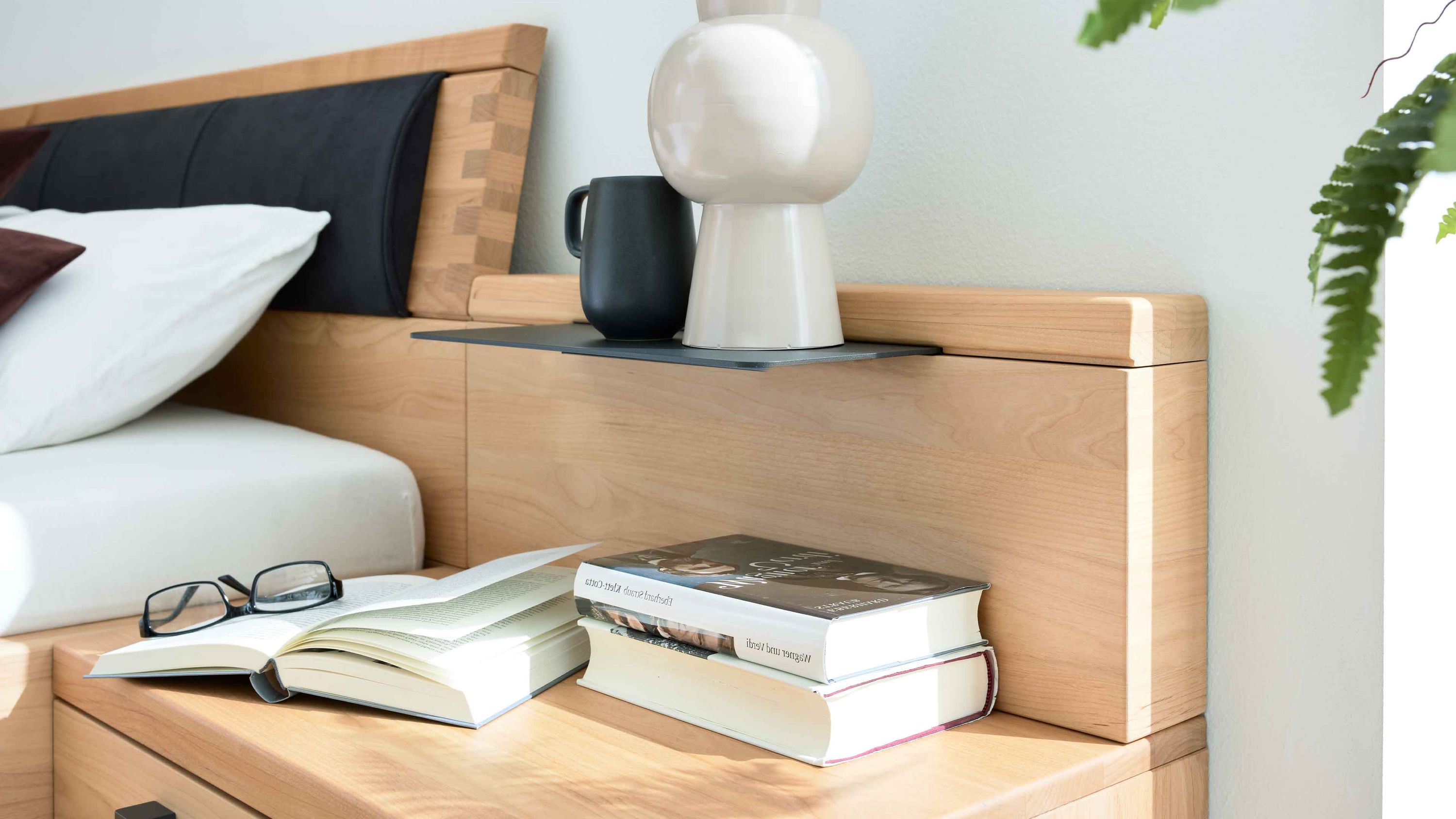 Paneelaufsatz-Set in Holzoptik mit schwarzem Ablagebrett Vase Tasse Büchern und Brille auf Holzfläche