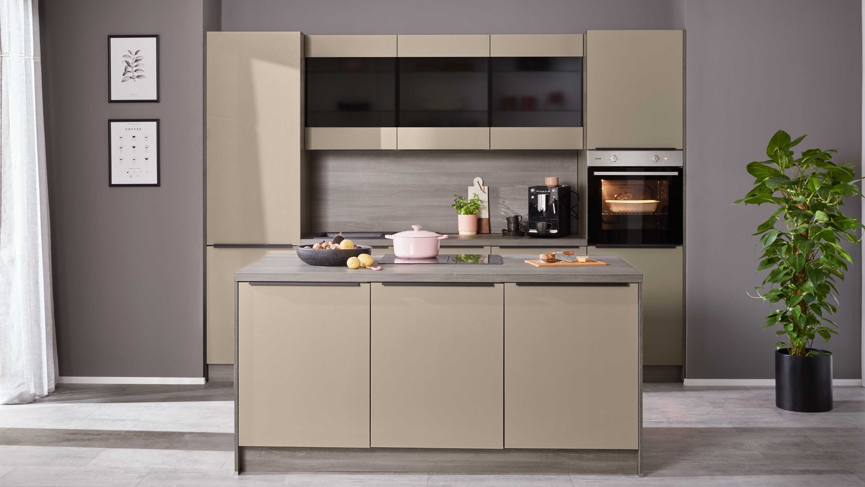 Beige Fronten Kücheninsel mit Geräten Kaffeemaschine; Pflanze rechts gerahmte Bilder links klare Linienführung