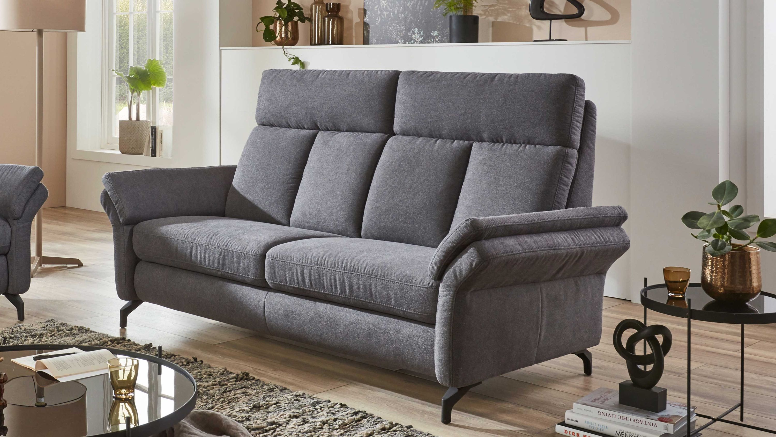 Zweisitziges Sofa mit anthrazitfarbenem Stoffbezug und gepolsterten Armlehnen auf schwarzen Beinen