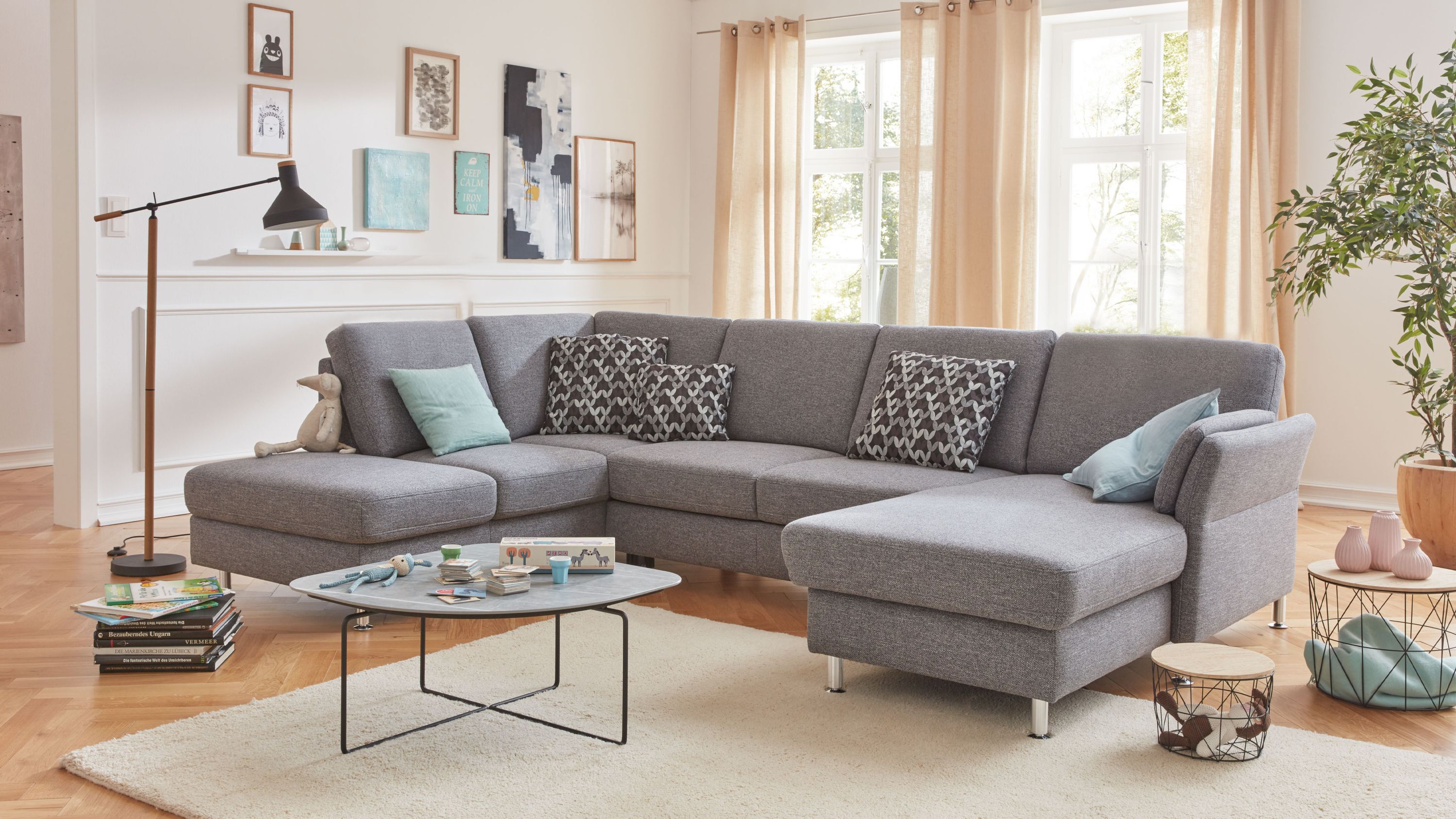 Ecksofa in U-Form mit stahlgrauem Flachgewebe und Metallfüßen mit Kissen in verschiedenen Mustern