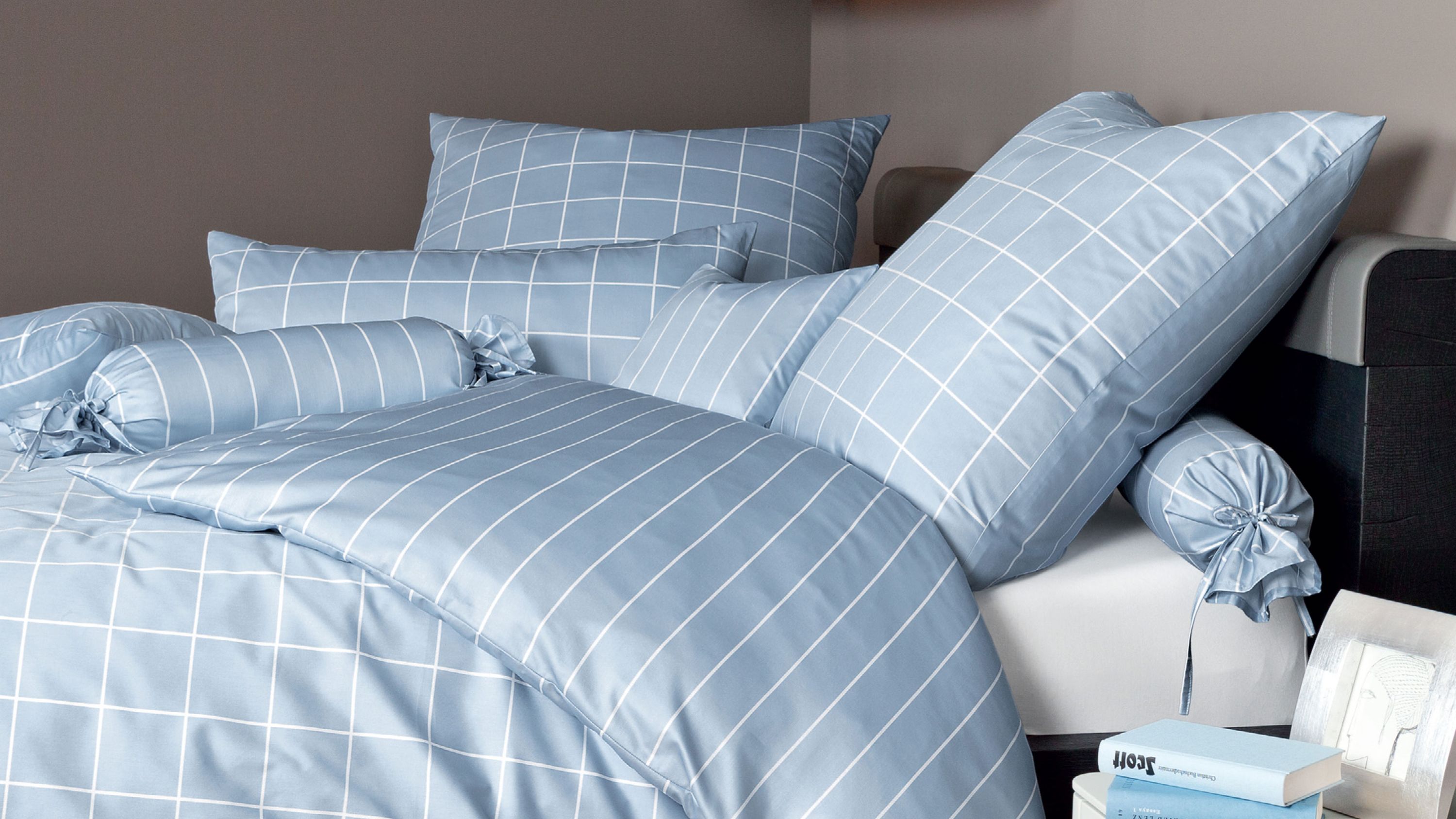 Bettwäsche-Set in perlblau mit weißen Linienmustern bestehend aus Kissen und Decke auf einem Bett