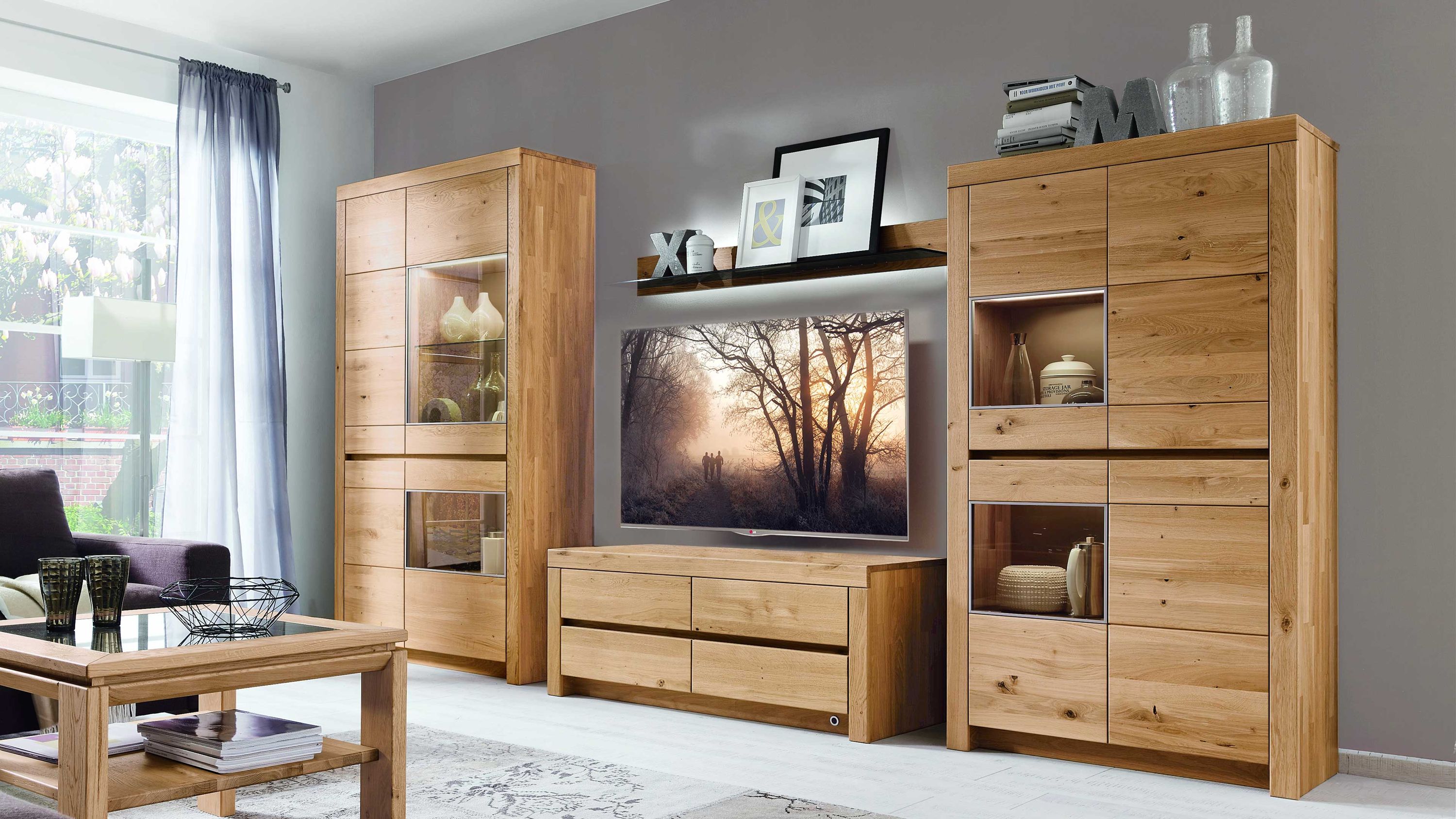 Wohnkombination aus hellem Holz mit Vitrinen und TV-Board Vierteilige Wohnkombination aus hellem Holz mit Vitrinen TV-Board und Wandregal in modernem Wohnzimmer