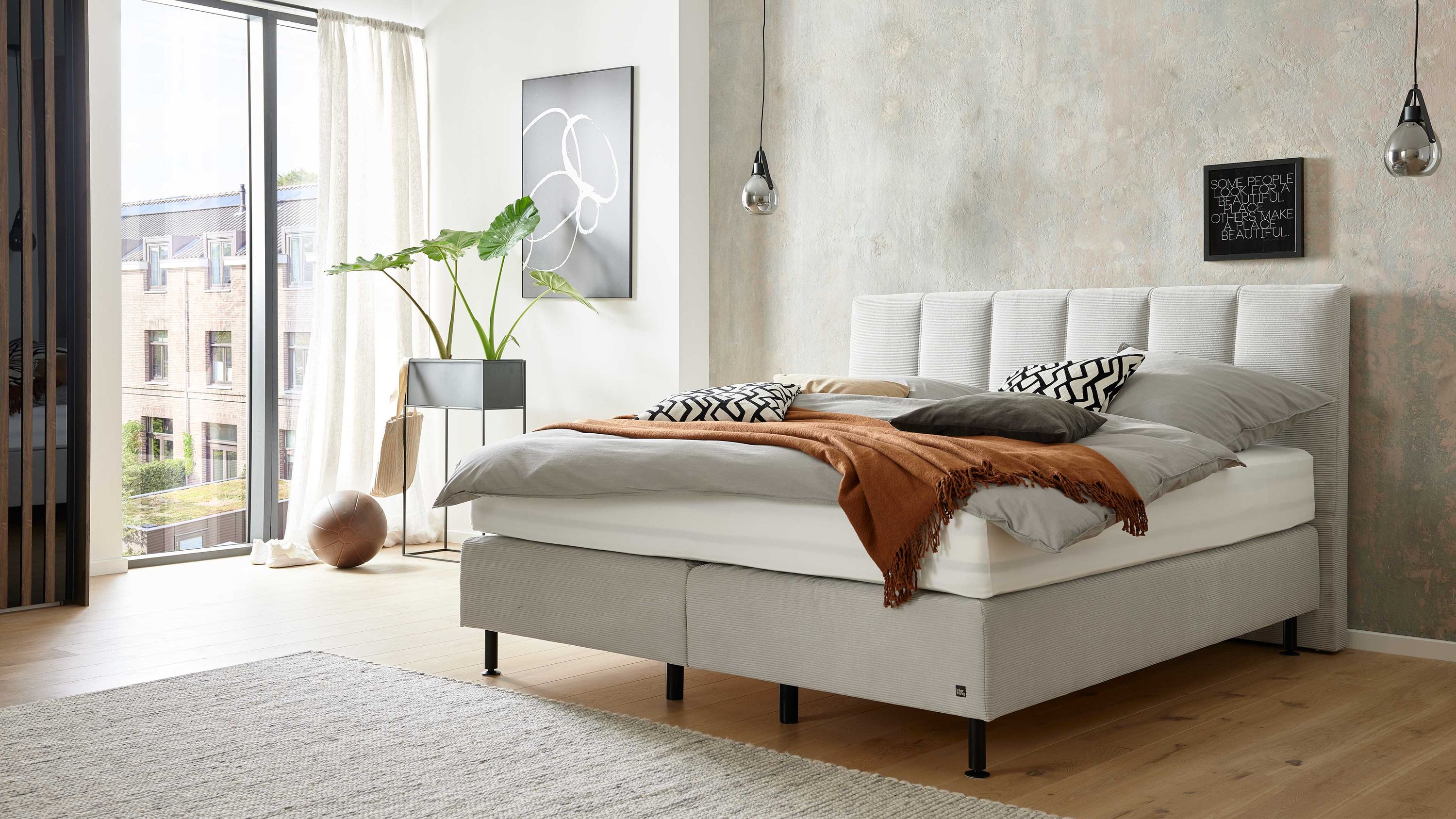 Boxspringbett mit silberfarbenem Feincordbezug und vertikal gestepptem Kopfteil in modernem Schlafzimmer