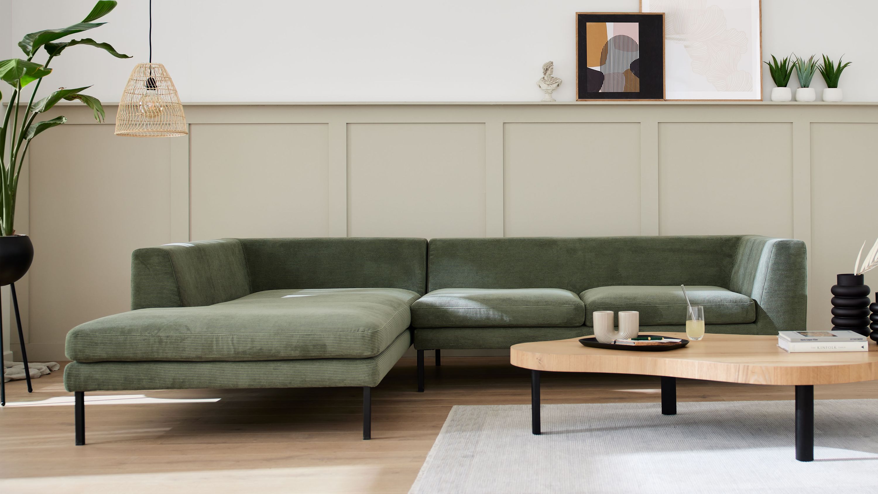 Ecksofa mit olivgrünem Cordbezug und schwarzen Metallfüßen in modernem Wohnzimmer
