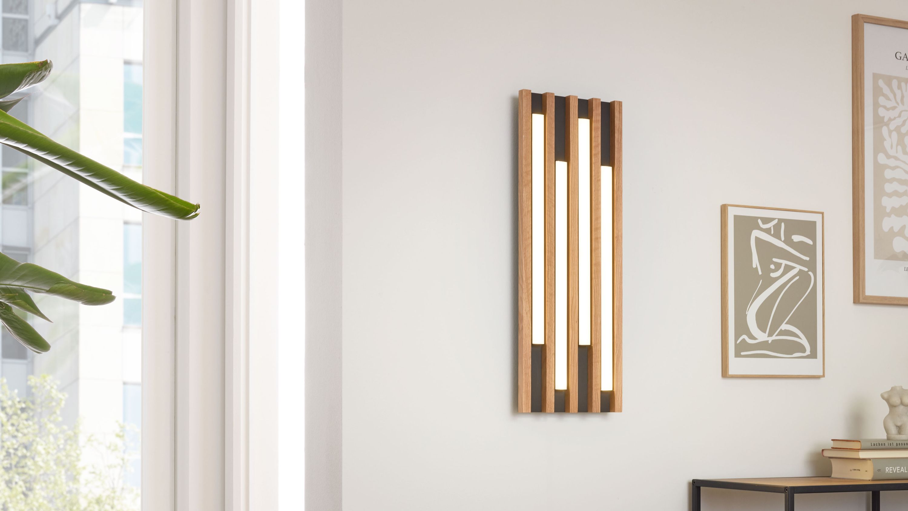 Vertikale Deckenlampe aus Holz mit vier länglichen weißen Leuchtflächen an der Wand
