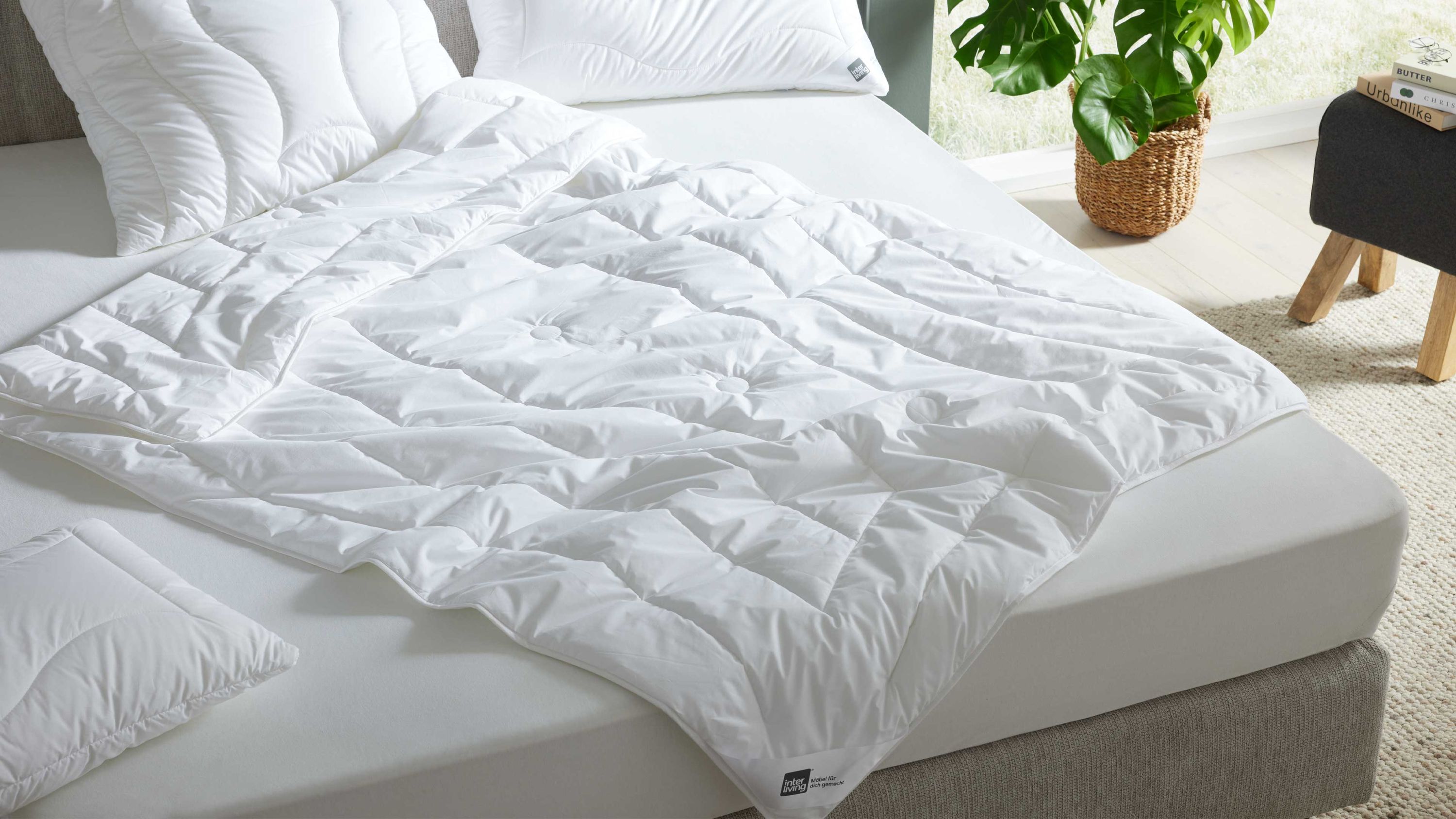 Weiße leichte Sommerbettdecke mit Steppmuster auf einem Bett mit weißem Spannbettlaken