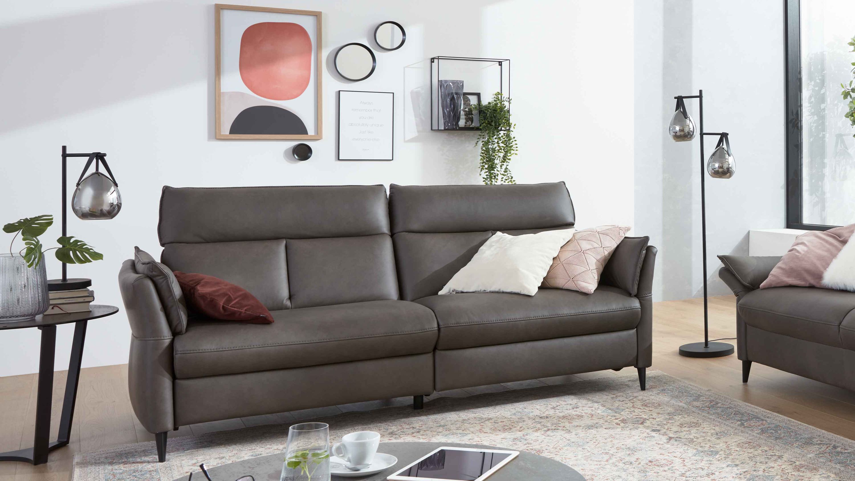 Dreisitziges graues Ledersofa mit hohen Lehnen und schwarzen Beinen in modernem Wohnzimmer