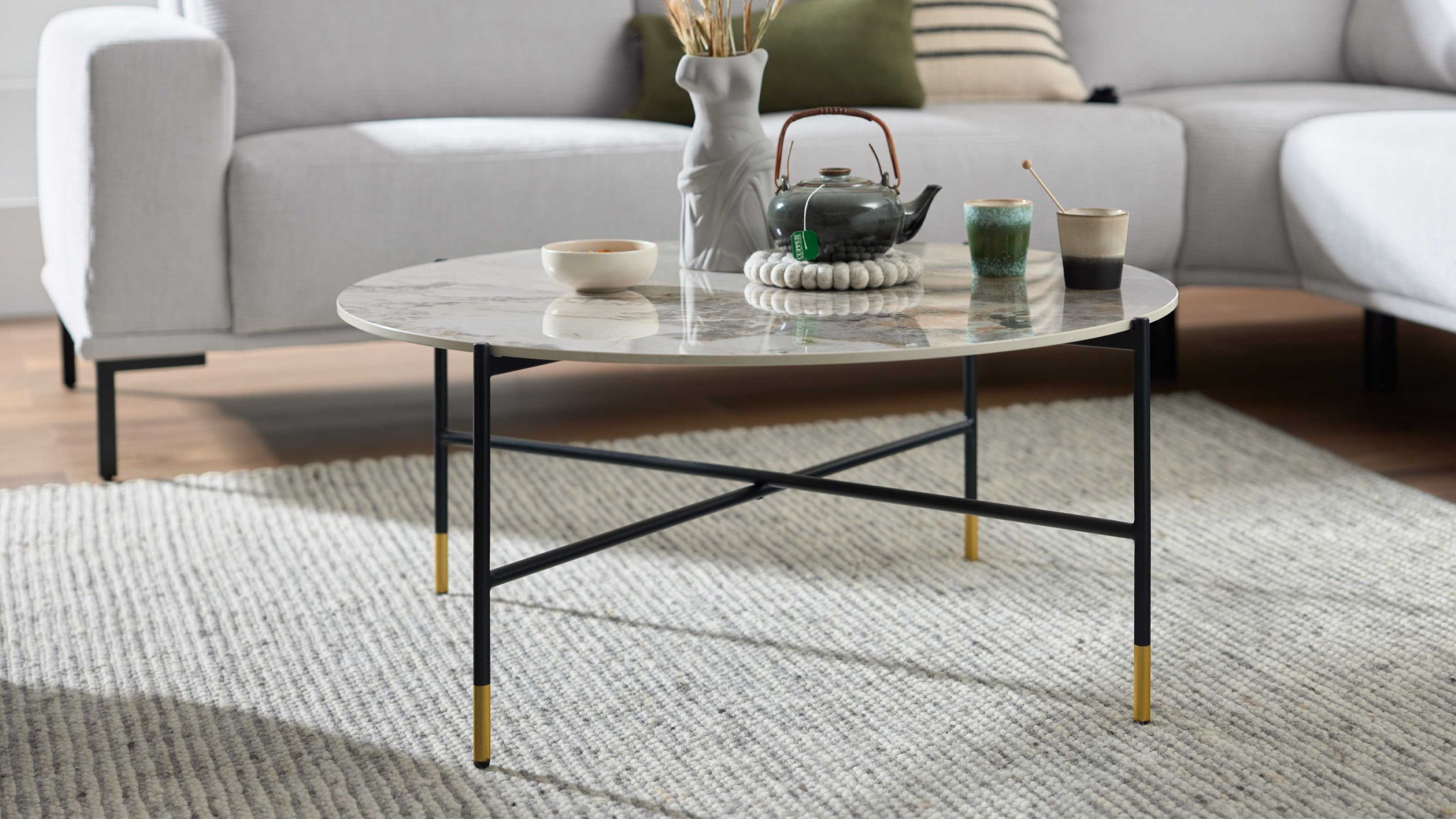 Runder Couchtisch mit marmorfarbener Platte und schwarzem Metallgestell Runder Couchtisch mit marmorfarbener Tischplatte und schwarzem Metallgestell mit goldfarbenen Enden