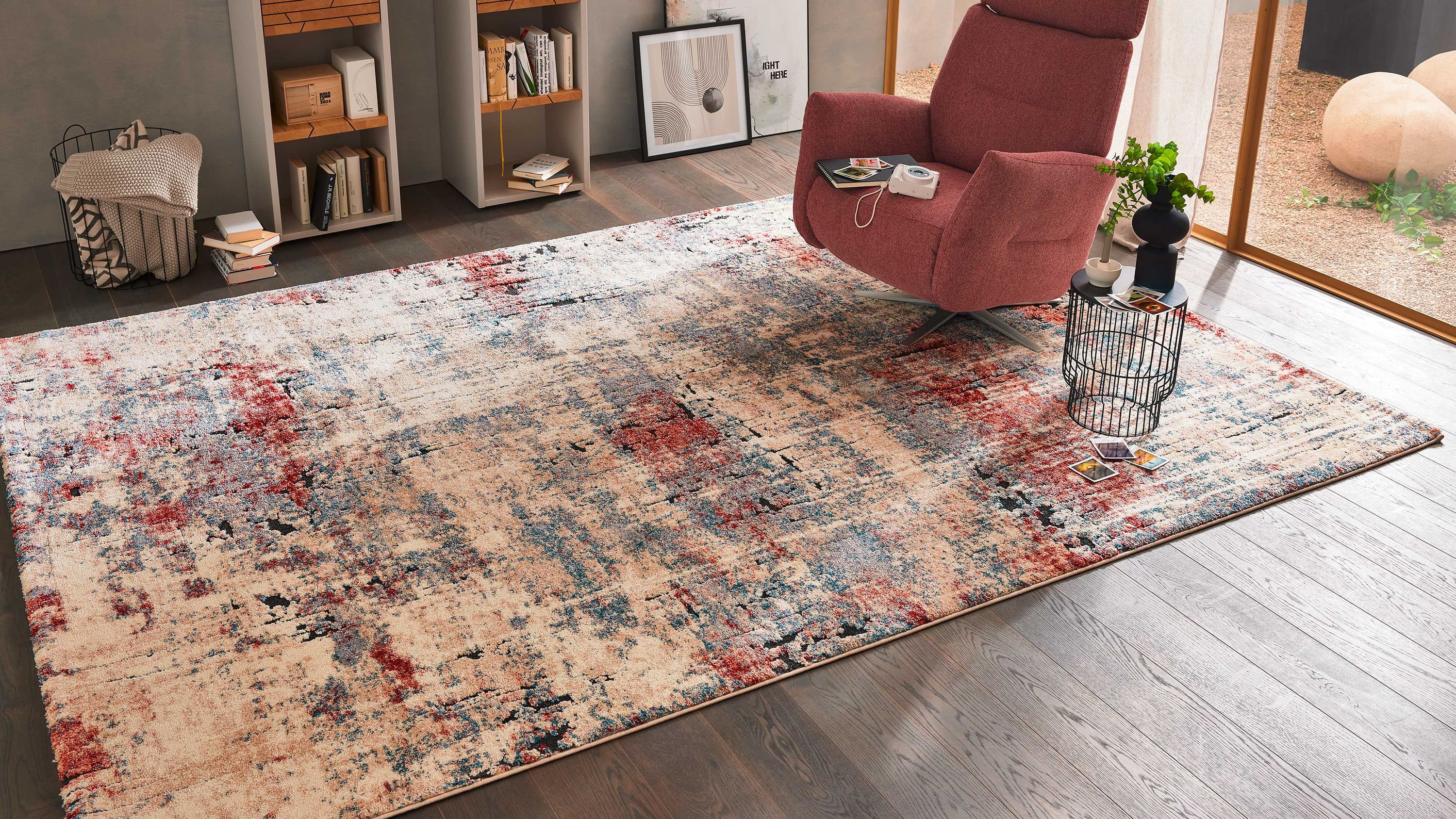 Rechteckiger Teppich mit abstraktem Muster in creme rot und blau auf dunklem Holzboden